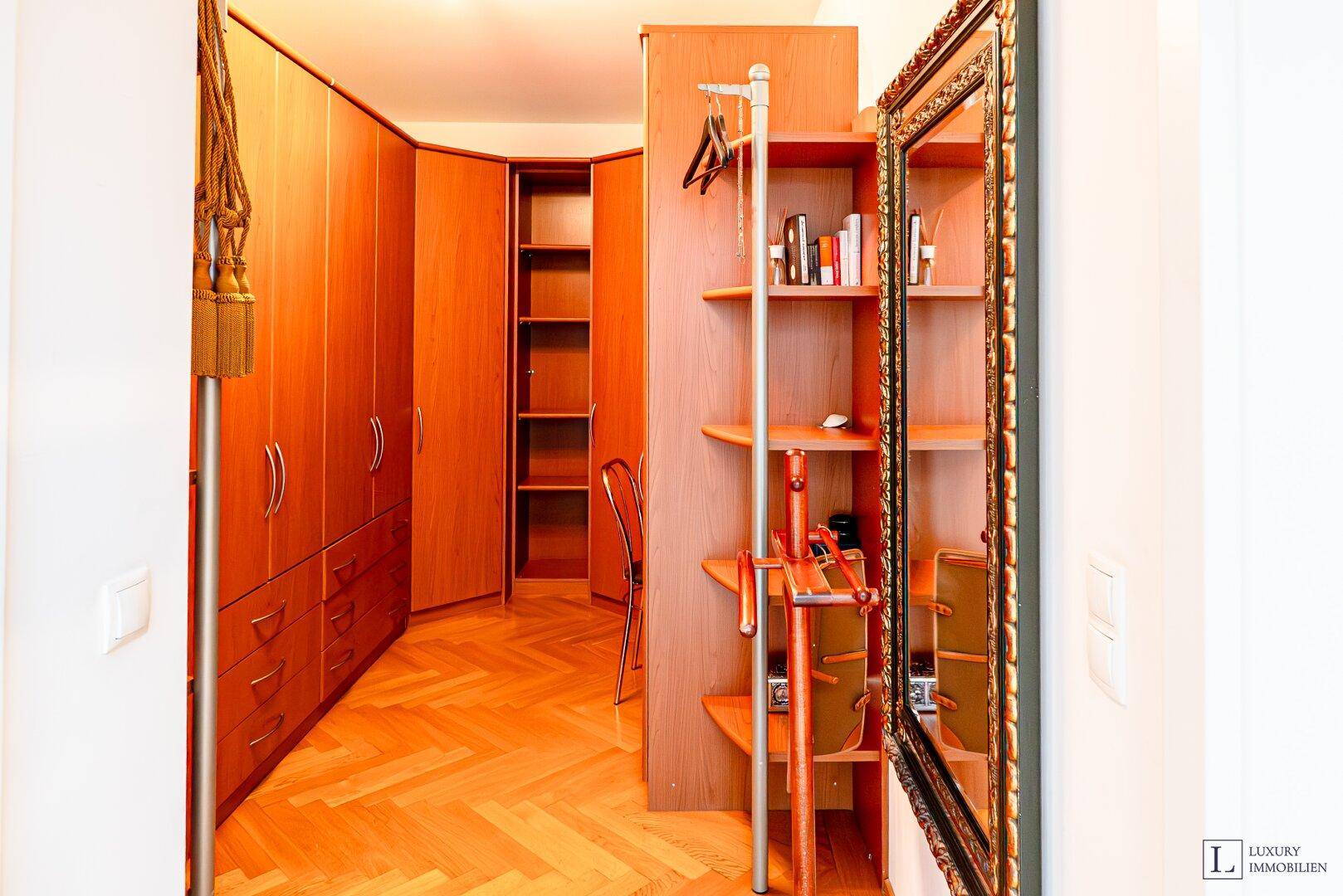 Begehbarer Kleiderschrank mit vielen Holzschränken und Regalen für umfangreichen Stauraum.