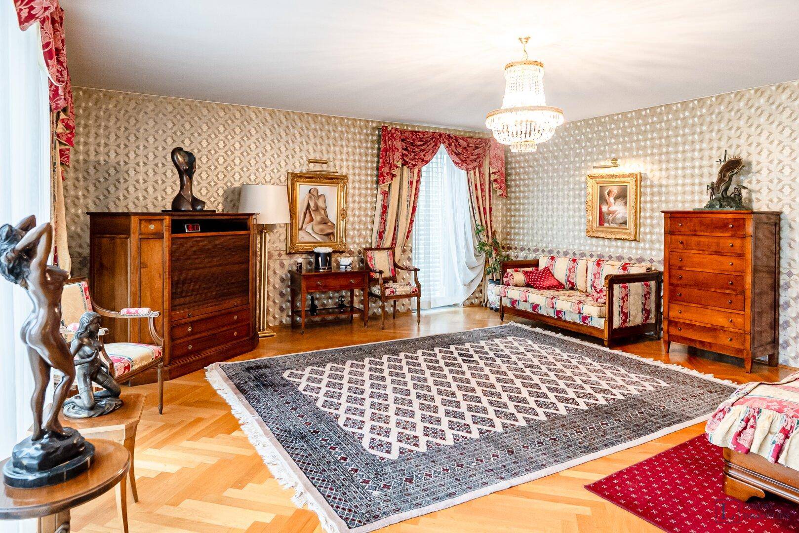 Geräumiges Wohn- oder Schlafzimmer mit klassischer Einrichtung, Teppich und Parkettboden.