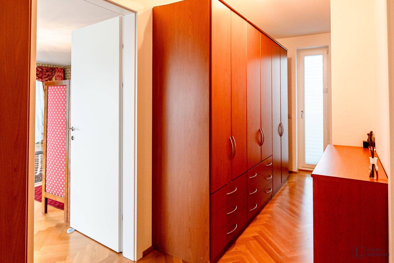 Heller Flur mit Einbauschränken aus Holz und Zugang zu weiteren Räumen.