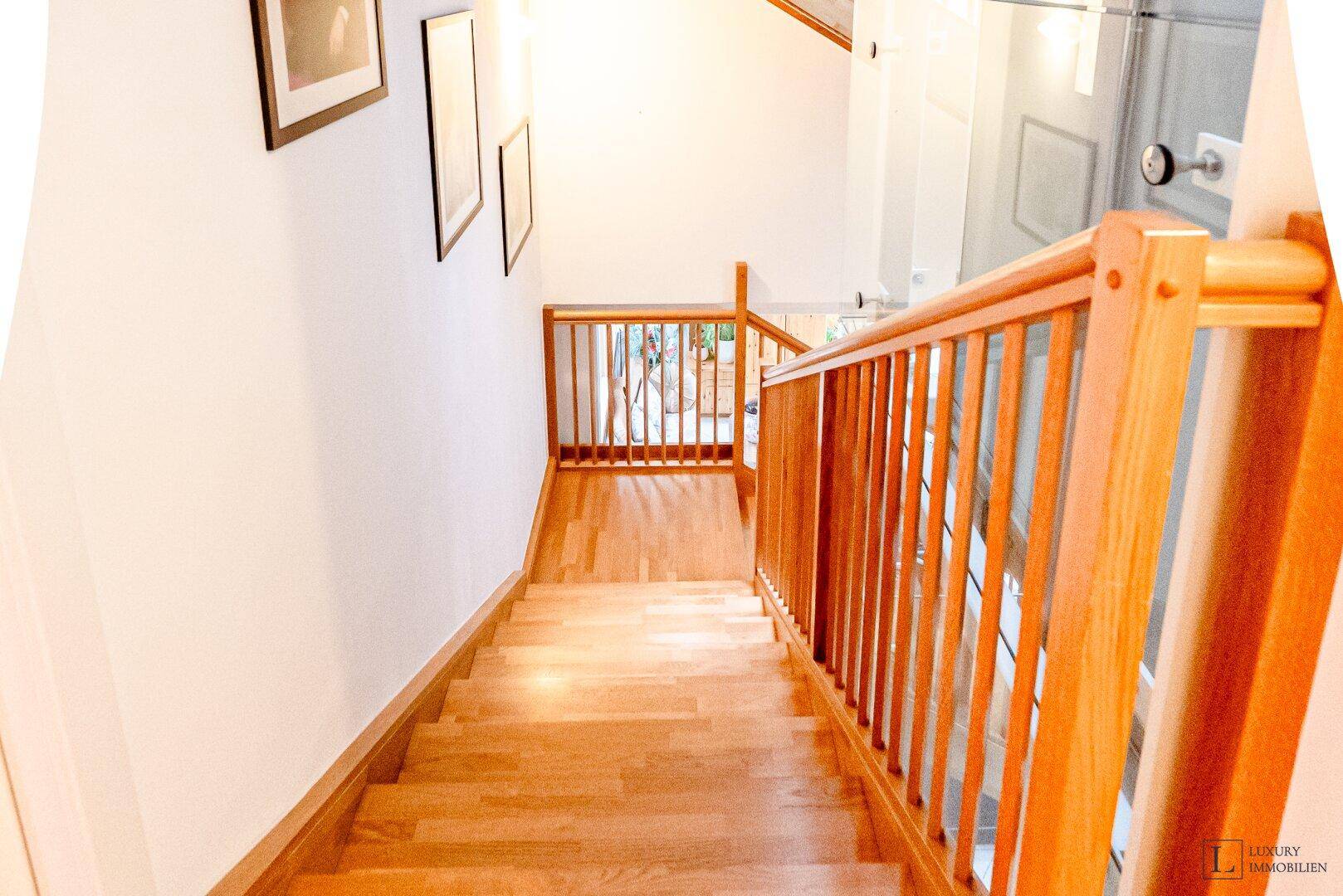Holztreppe mit Geländer, die verschiedene Etagen des Hauses stilvoll verbindet.