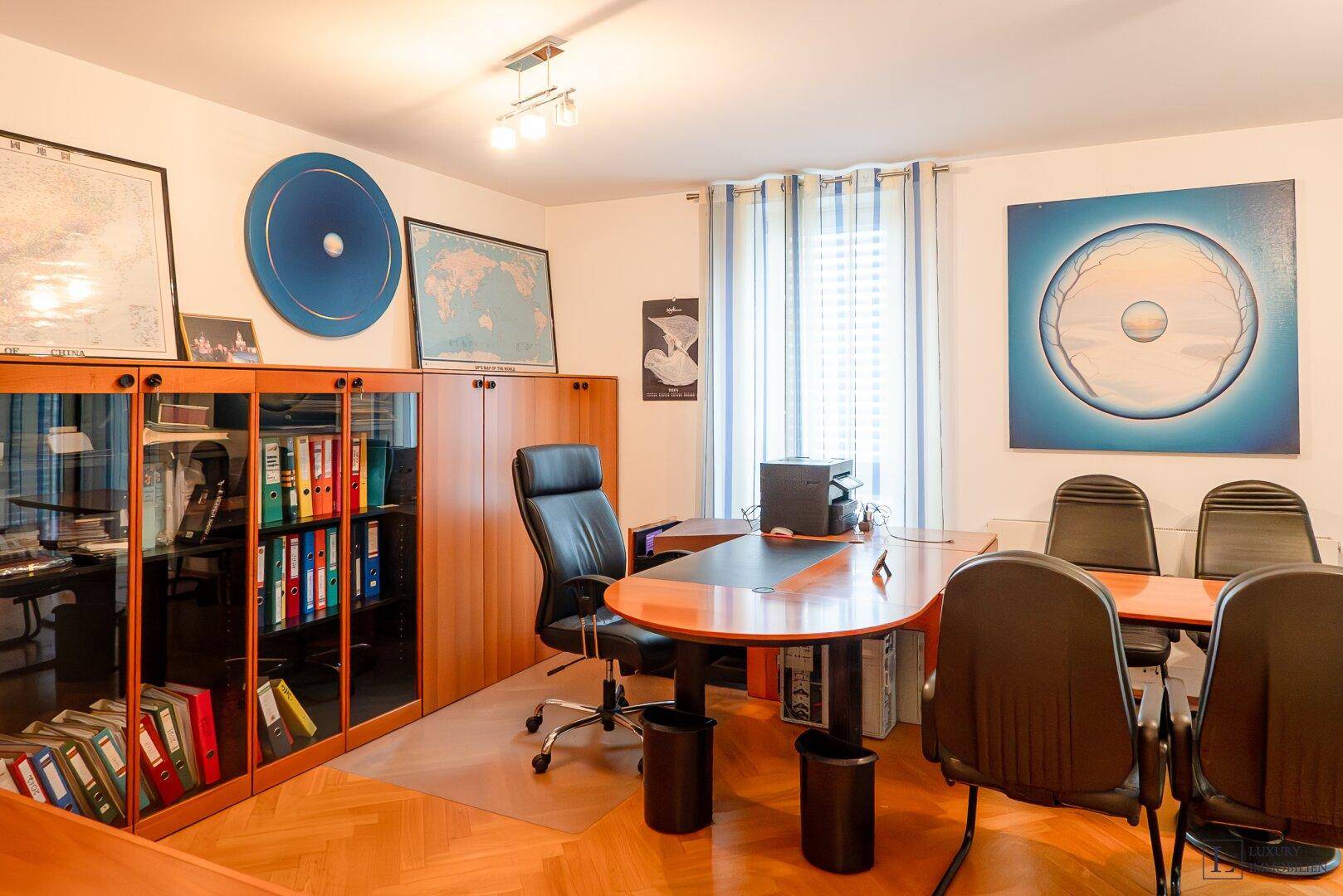 Helles Büro mit großem Schreibtisch, Bürostühlen und praktischen Bücherregalen.
