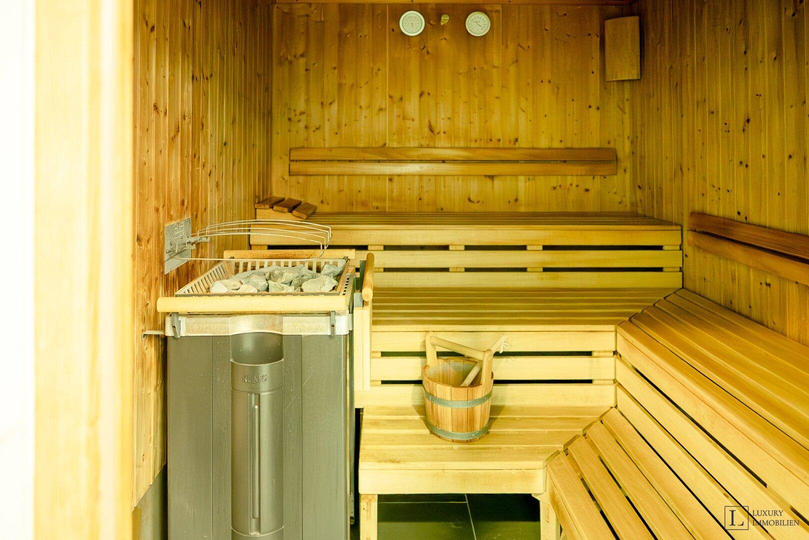 Geräumige Holzsauna mit Heizofen und mehreren Sitzebenen für entspannende Stunden.
