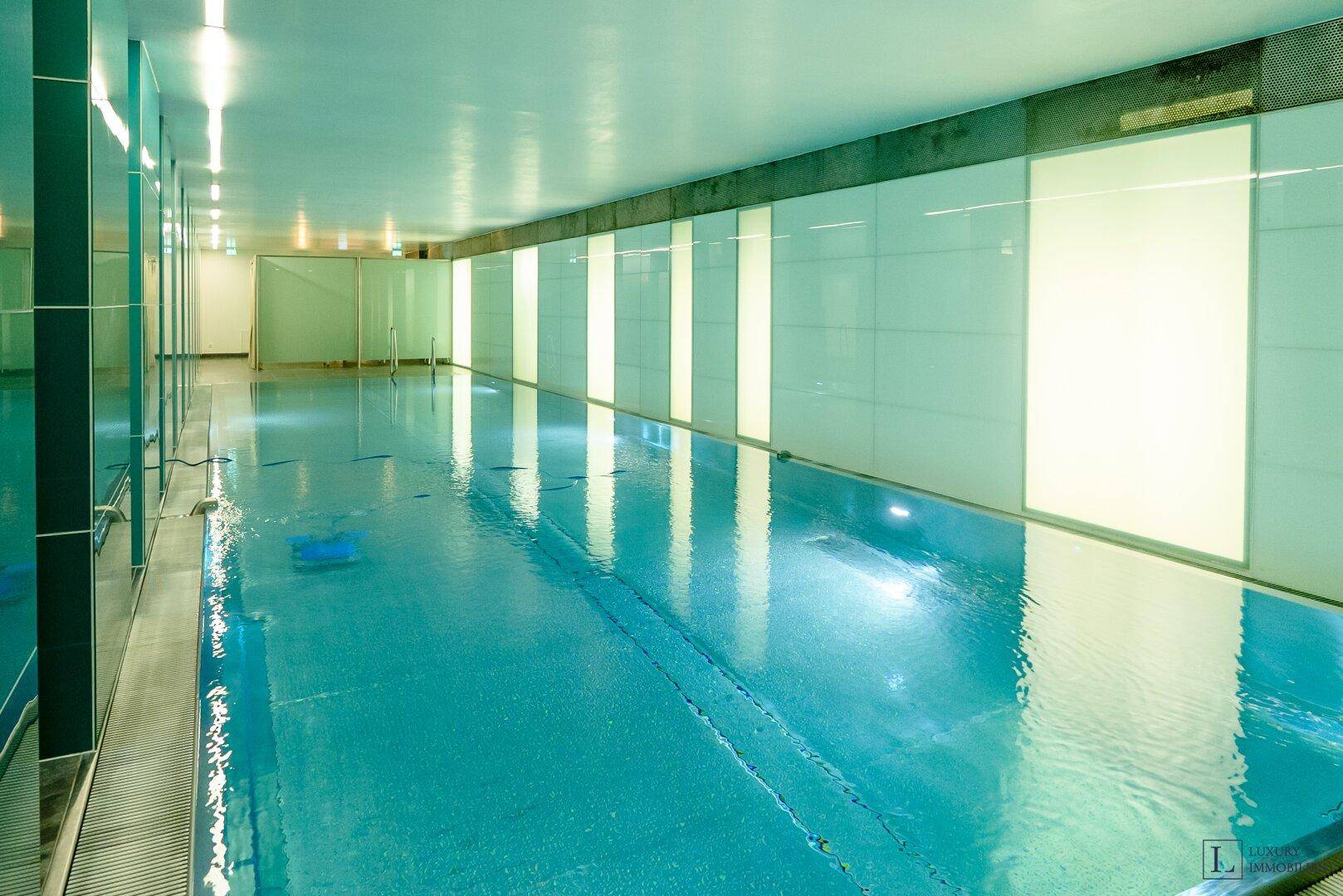 Großes Hallenbad mit klarem Wasser und indirekter Beleuchtung, schafft eine ruhige Atmosphäre.
