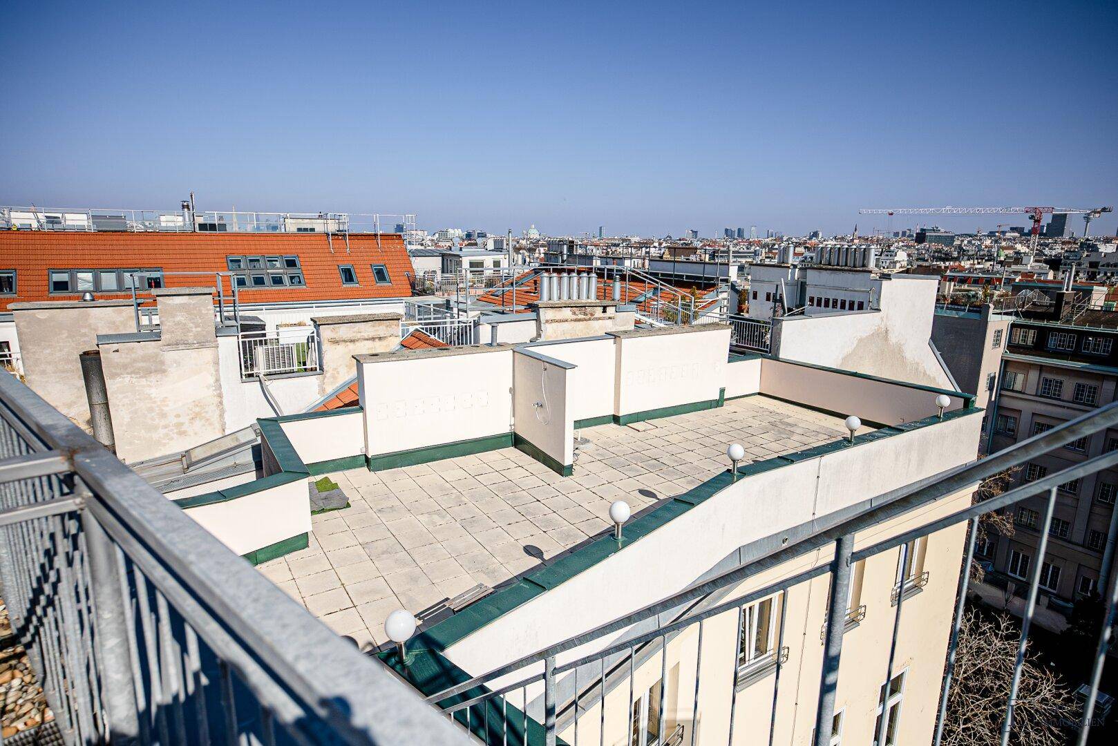 Weitläufige Dachterrasse mit Stadtblick und umliegenden Gebäuden.