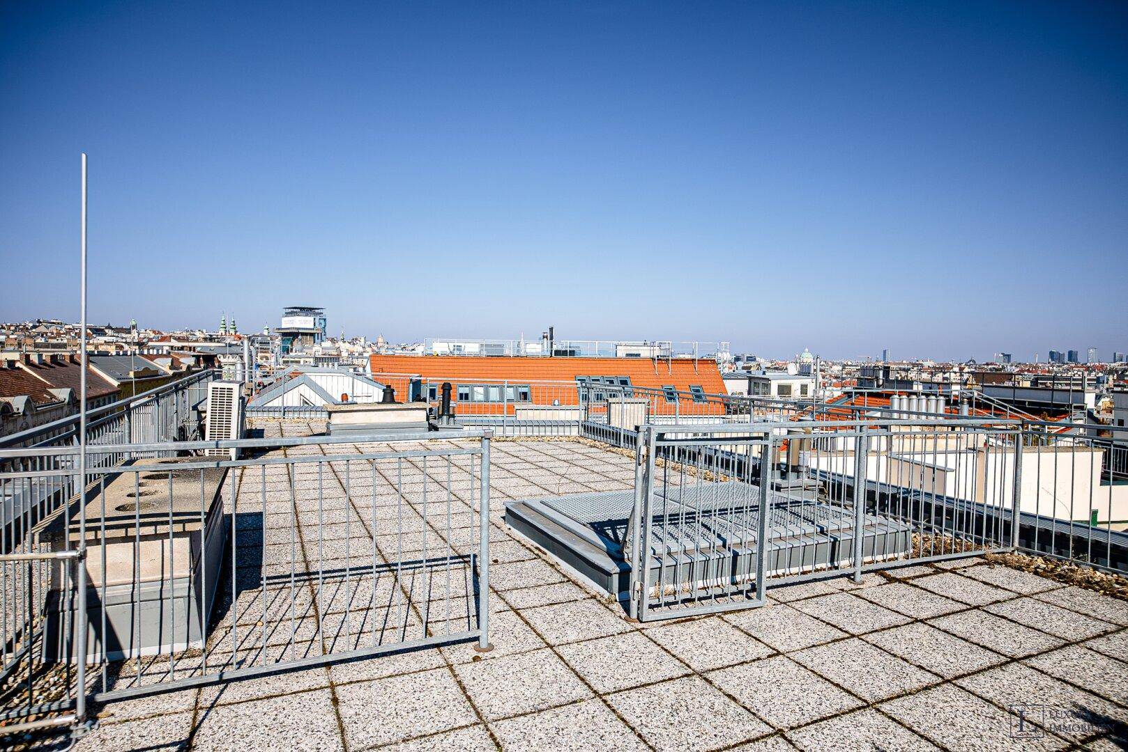 Geräumige Dachterrasse mit Fliesenboden und Metallgeländer, ideal für Entspannung im Freien.