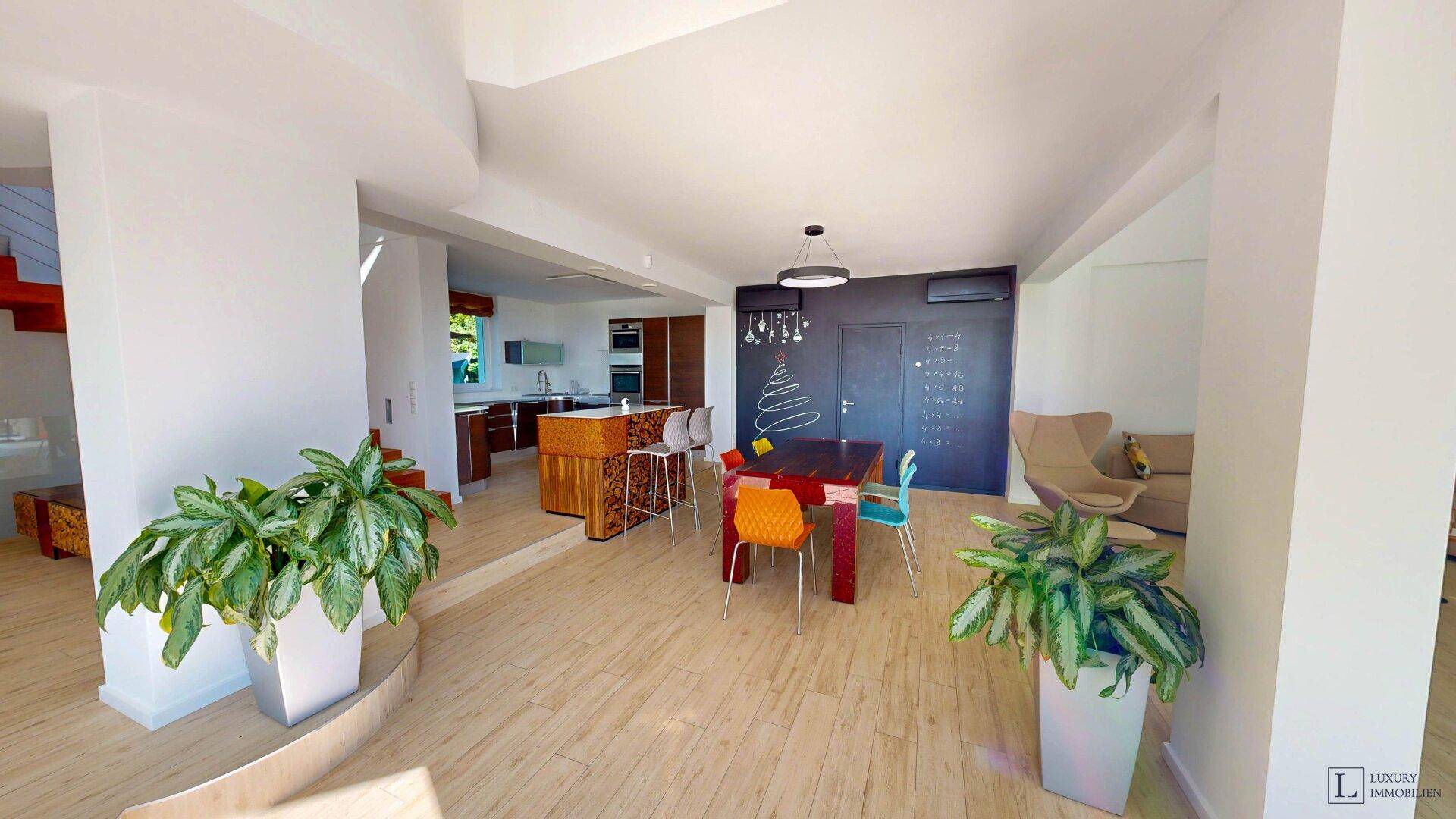 Moderne offene Küche mit Essbereich, Holzelementen und einer Tafelwand im Hintergrund.