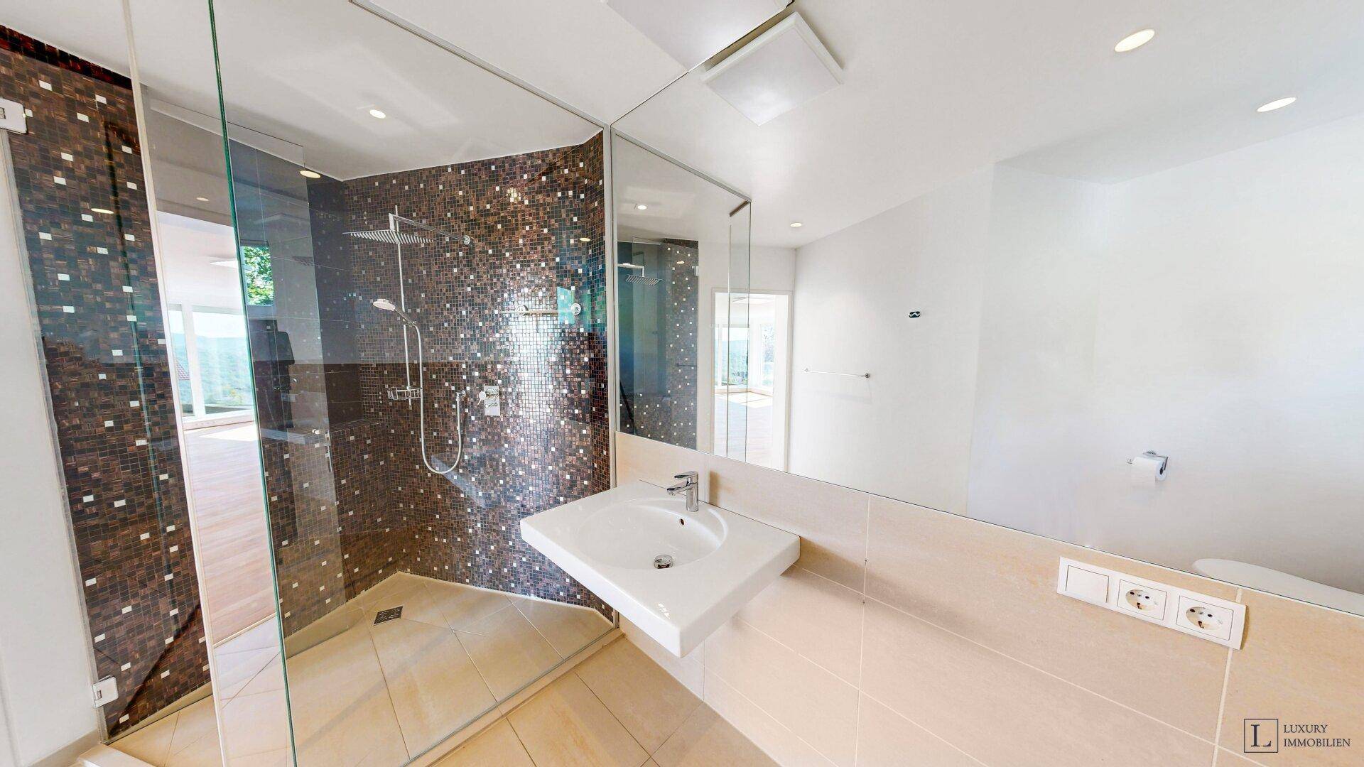 Modernes Badezimmer mit begehbarer Dusche, Mosaikfliesen und einem großen Spiegel über dem Waschbecken.