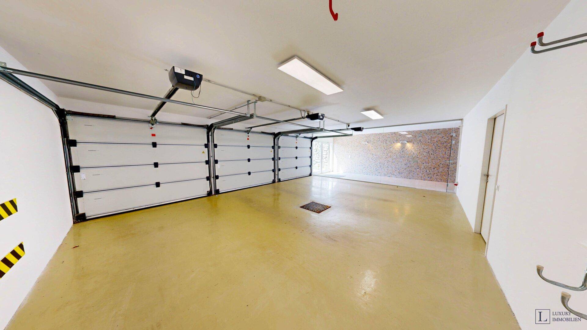 Geräumige Garage mit drei Sektionaltoren und ausreichend Platz für mehrere Fahrzeuge.