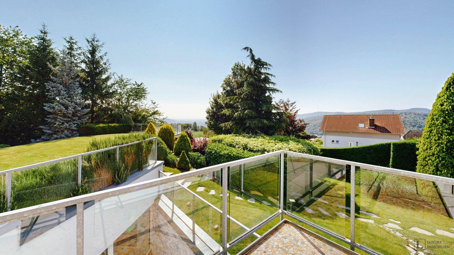Terrasse mit Glasgeländer bietet einen weiten Blick über die grüne Landschaft und die Umgebung.