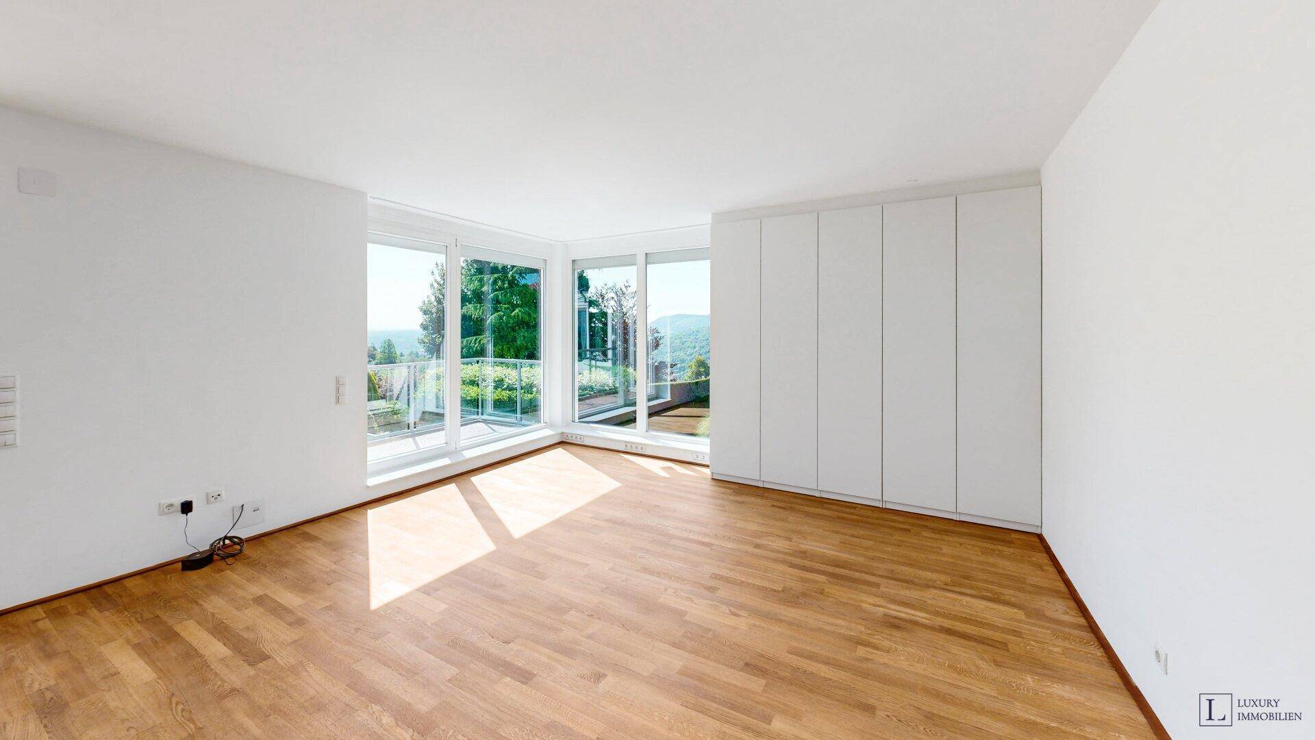 Helles Schlafzimmer mit Holzboden, Einbauschränken und Panoramablick auf Berge und Grünflächen.