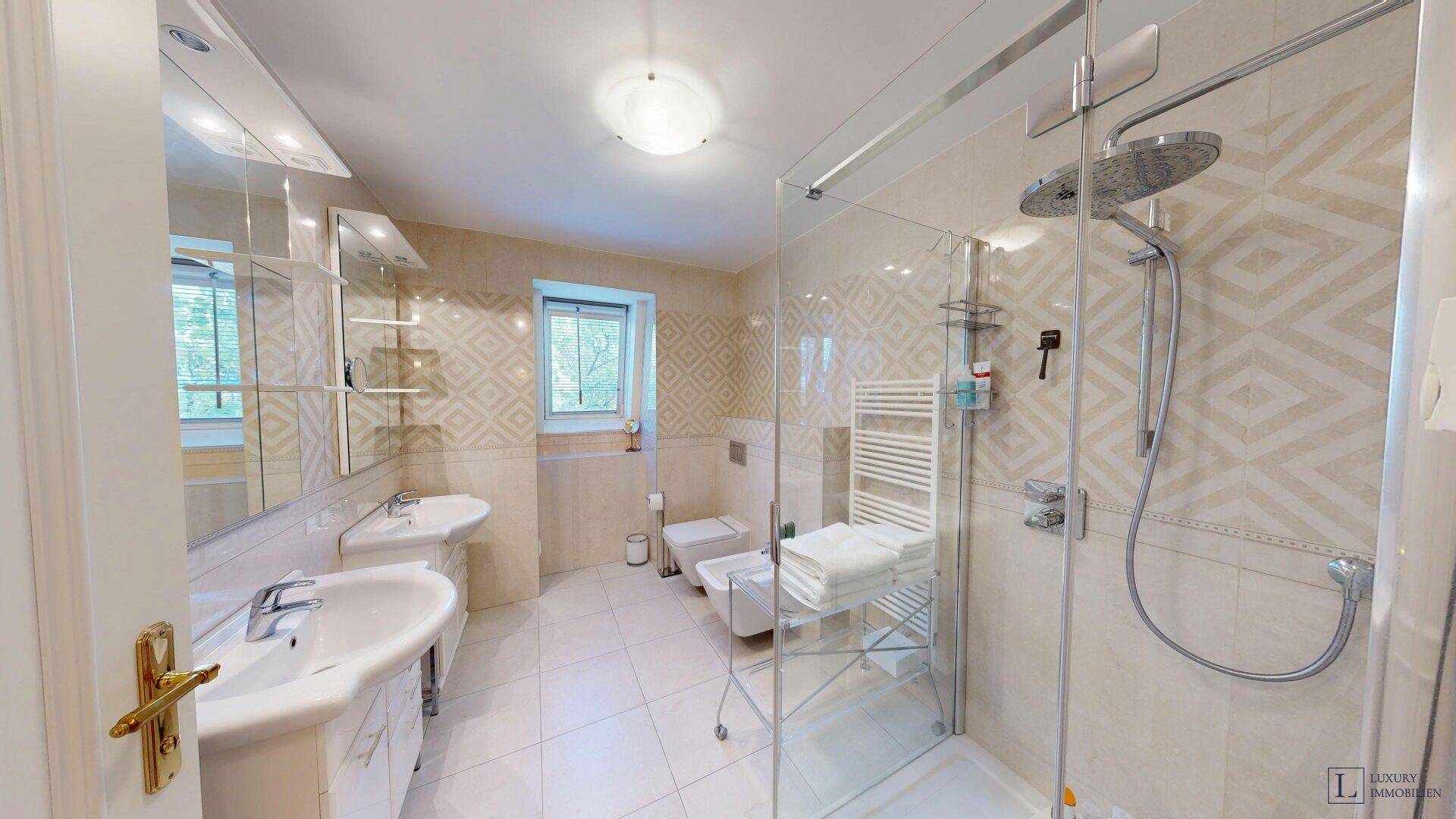 Modernes Badezimmer mit Doppelwaschbecken, großer Duschkabine und Fenster.