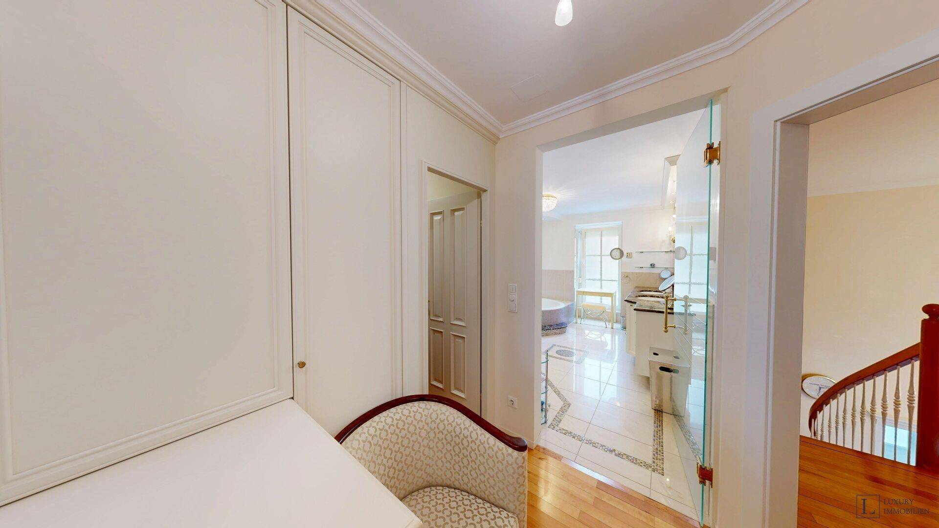 Heller Flur mit Holzboden und Blick in ein luxuriöses Badezimmer mit Badewanne.