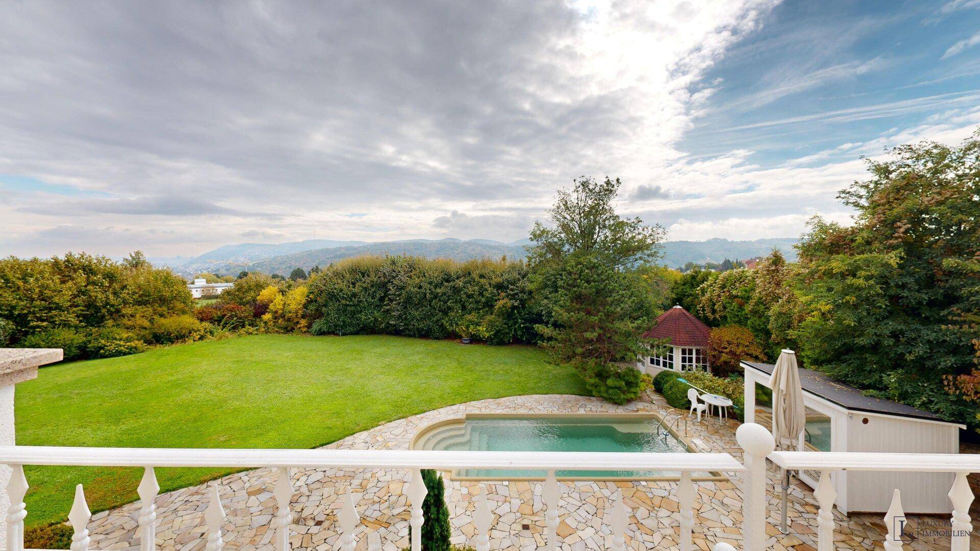 Weitläufiger Garten mit Pool und Panoramablick auf die umliegende Landschaft und Berge.