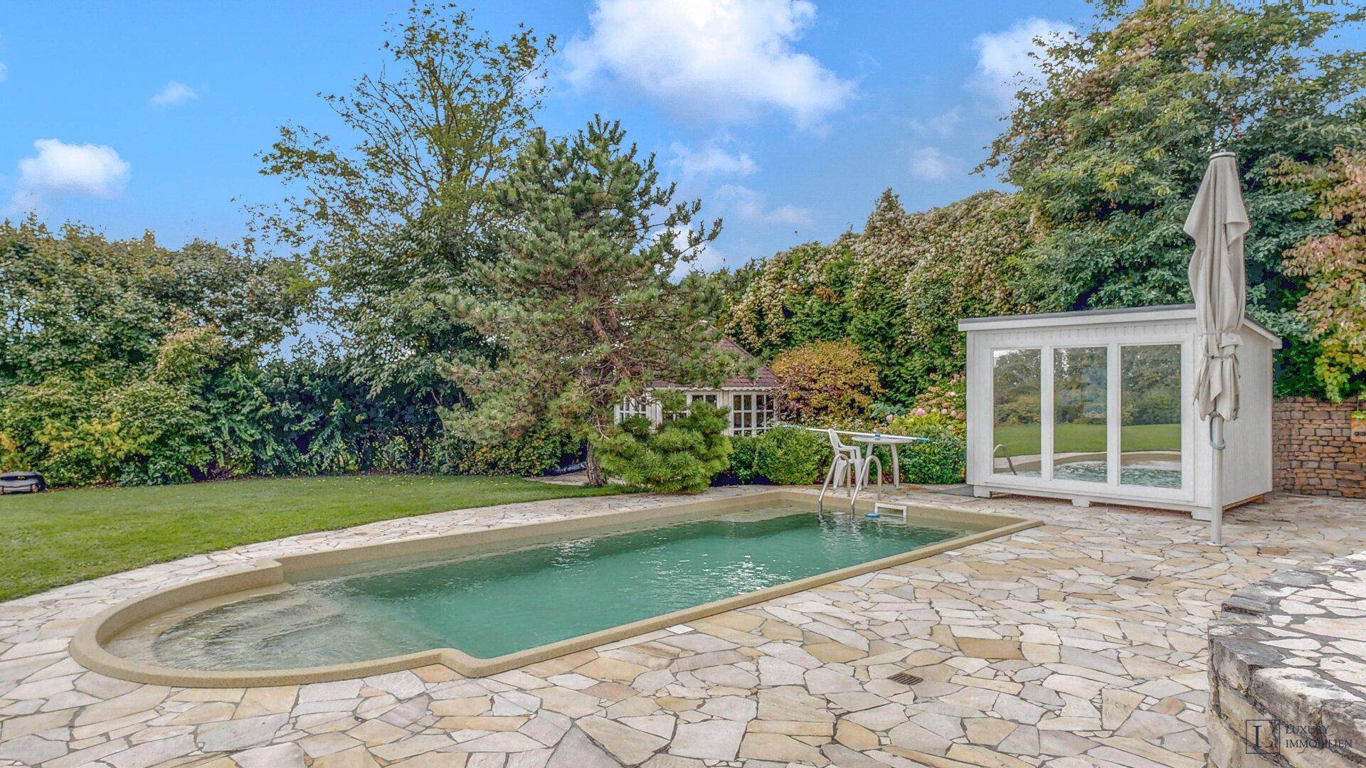 Gepflegter Gartenbereich mit Pool, Sonnenterrasse und einem kleinen Gartenhaus.