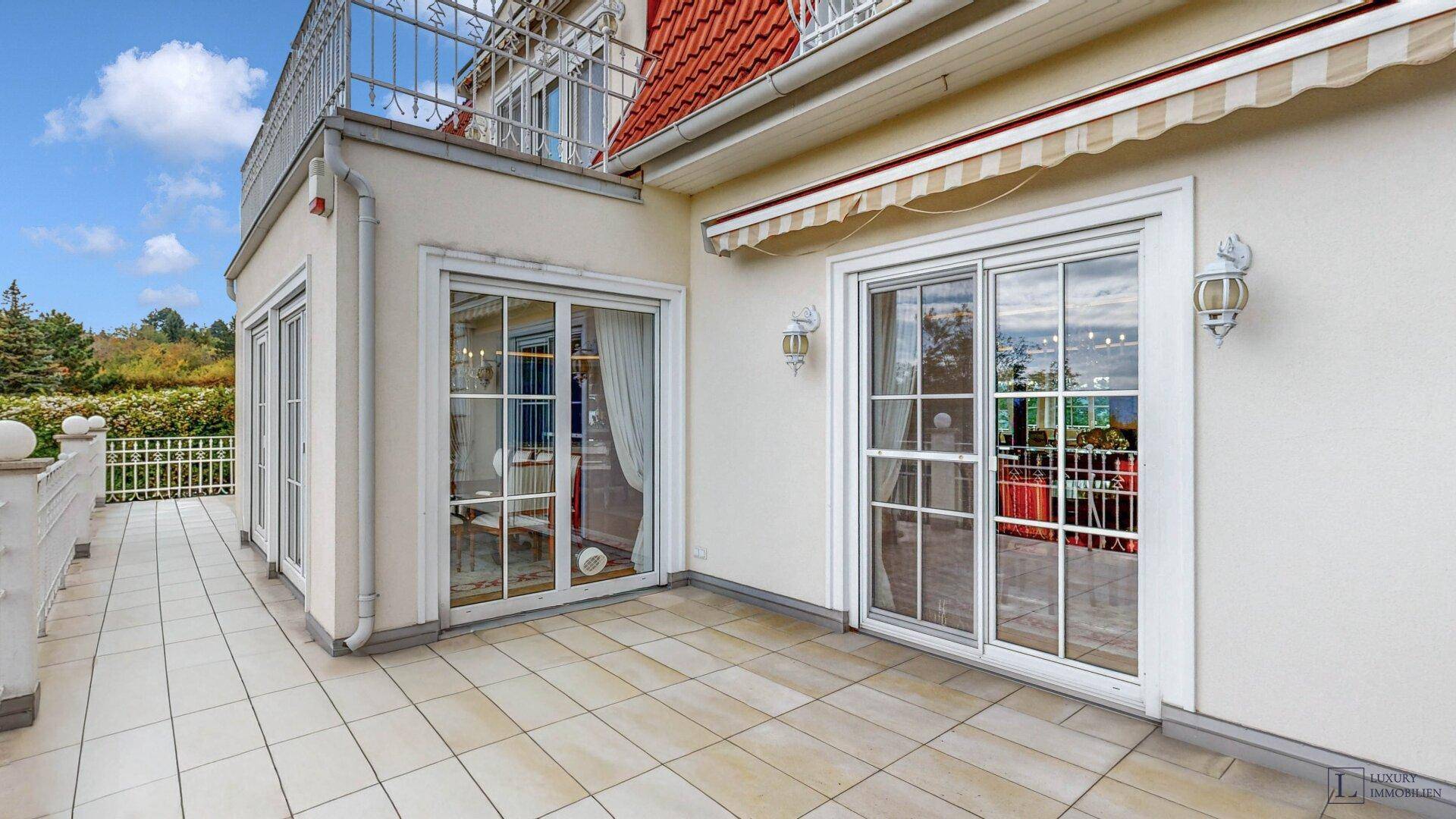 Geräumige Terrasse mit Fliesenboden und Zugang zu den Innenräumen der Villa.