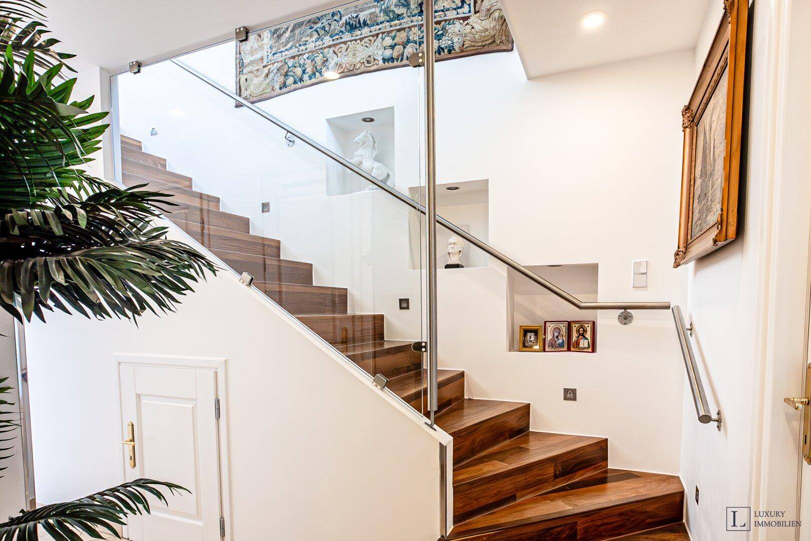 Elegante Holztreppe mit Glasgeländer und integrierten Nischen in einem modernen Ambiente.