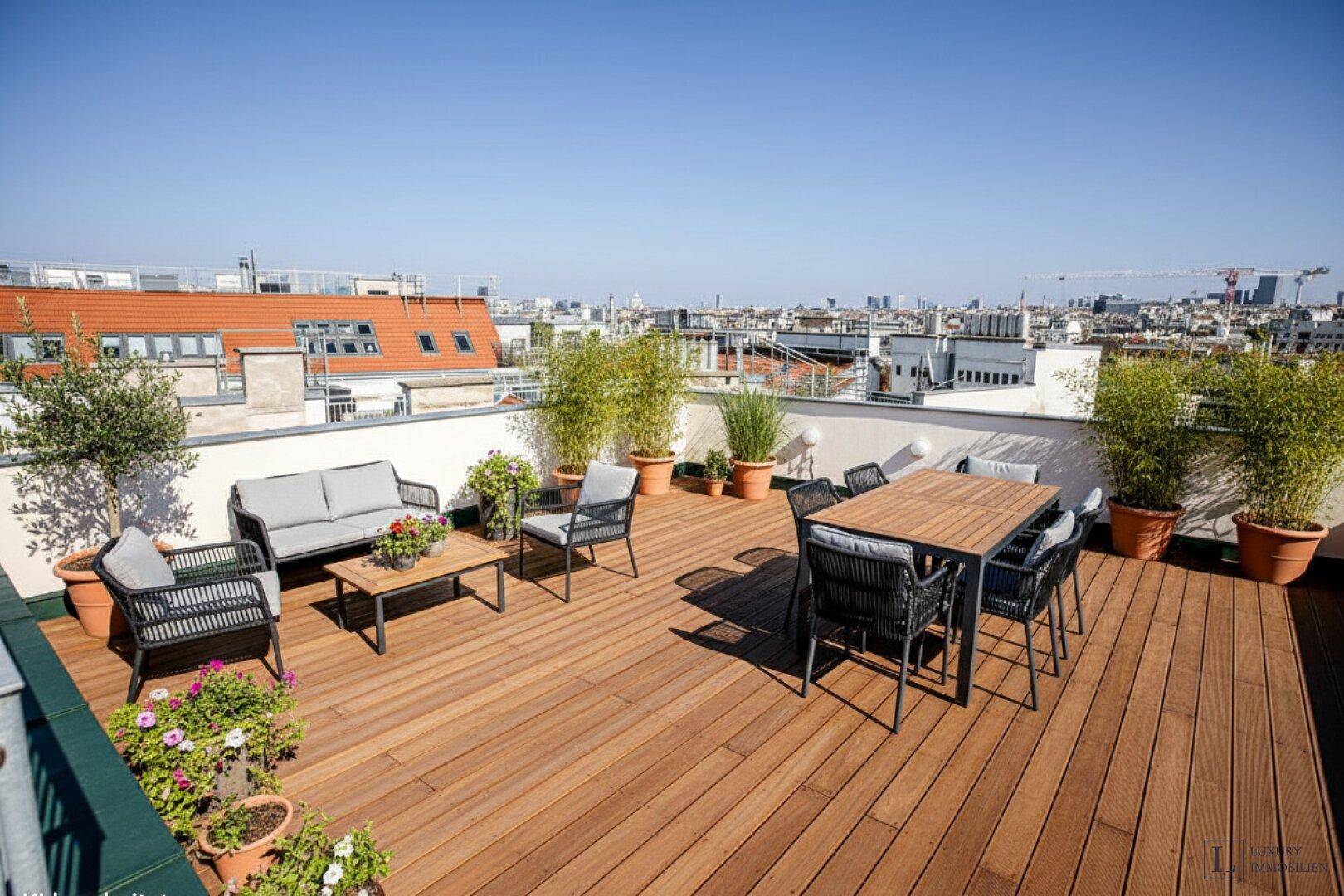Großzügige Dachterrasse mit Holzdeck, bequemen Sitzgelegenheiten und Stadtblick.