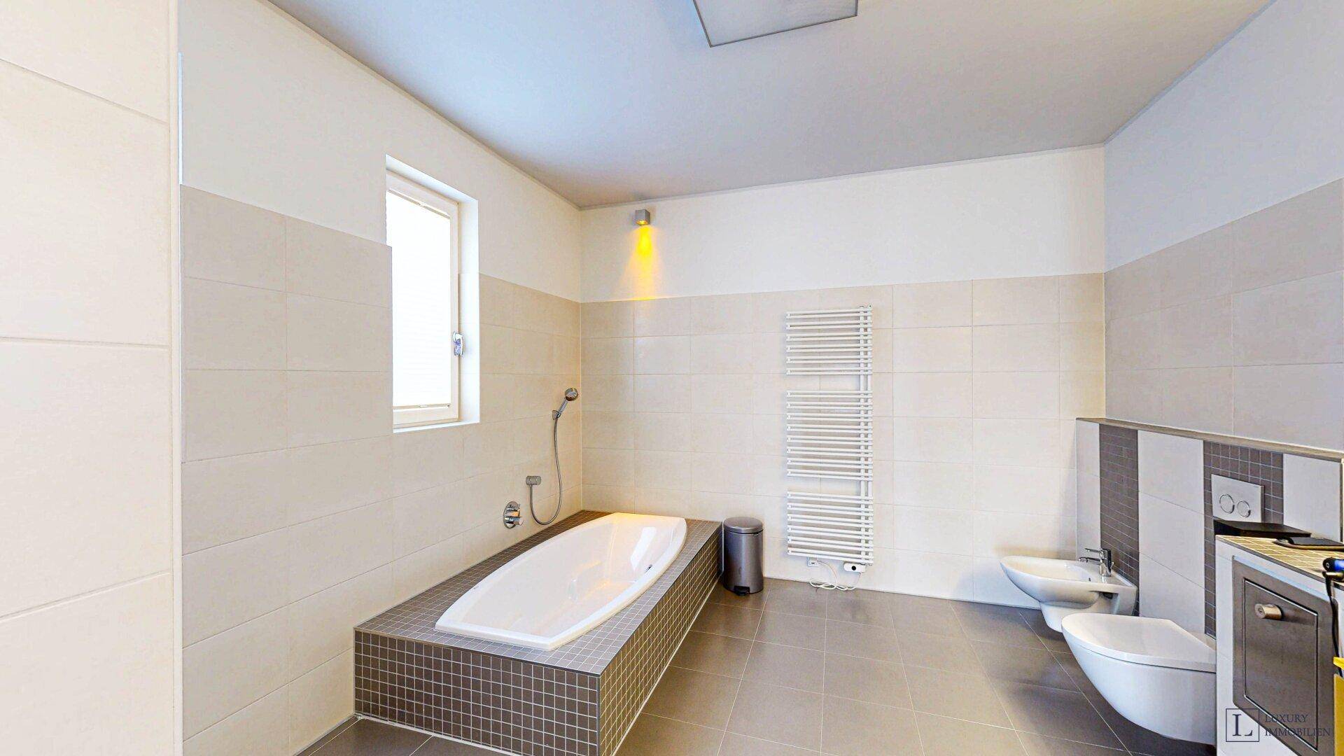 Modernes Badezimmer mit Badewanne, Bidet, WC und beheiztem Handtuchhalter.