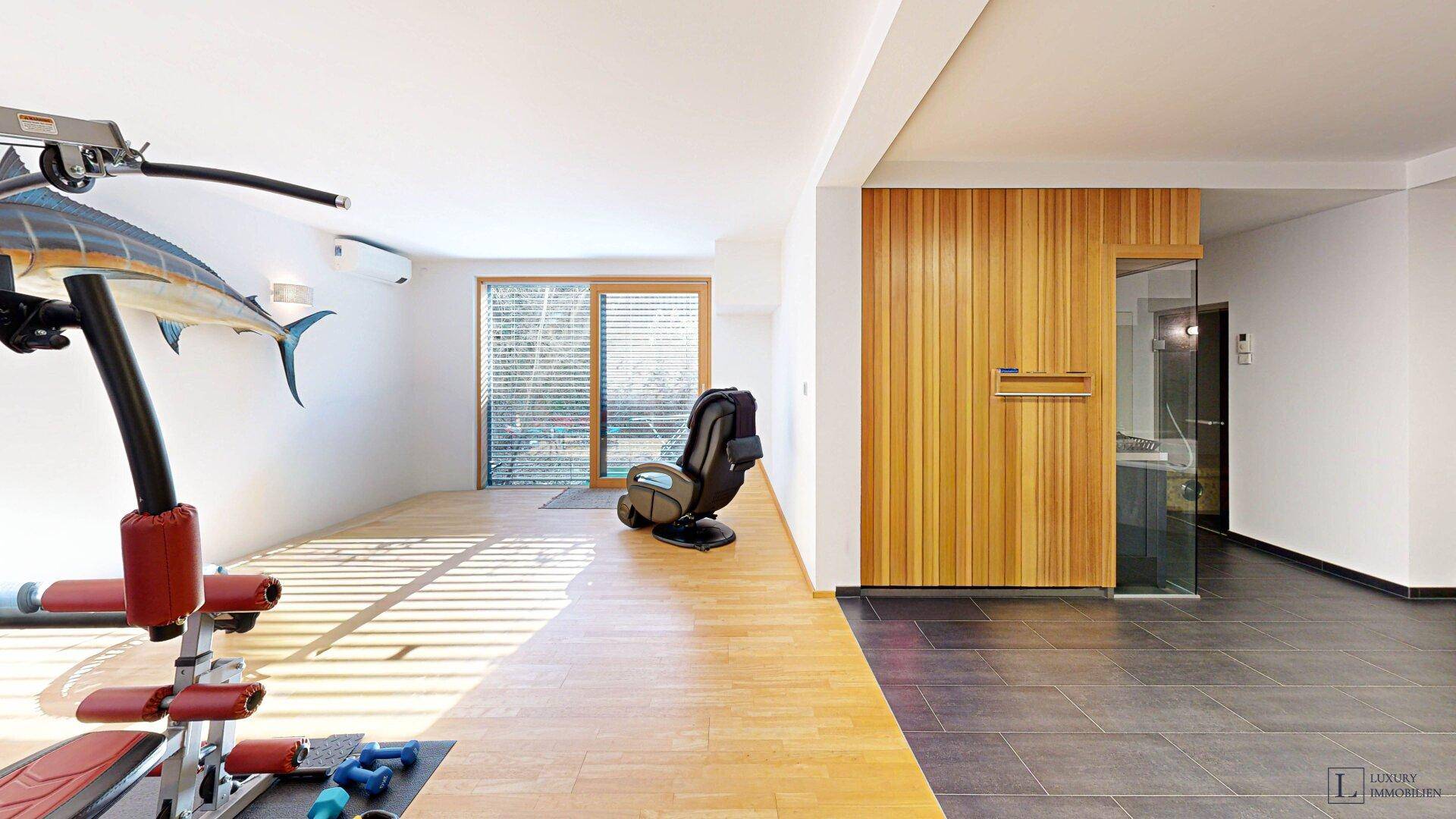 Geräumiger Wellnessbereich mit Fitnessgeräten und Zugang zur Sauna.
