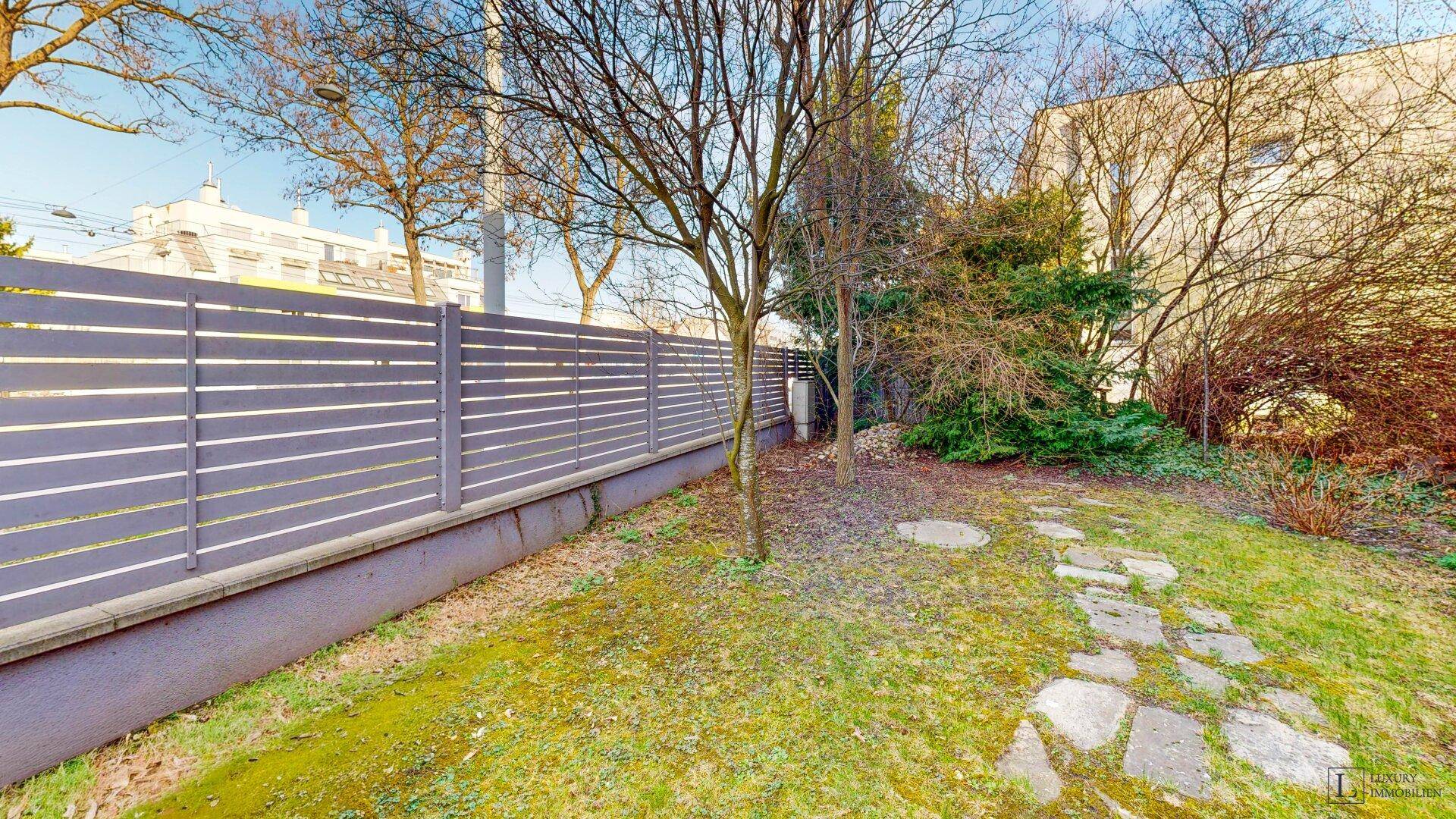 Gepflegter Gartenbereich mit Rasenfläche und modernem Zaun.