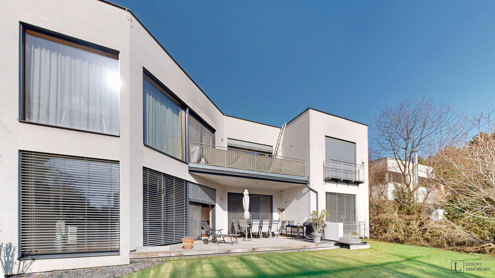 Rückseite des modernen Hauses mit großer Terrasse und Garten.