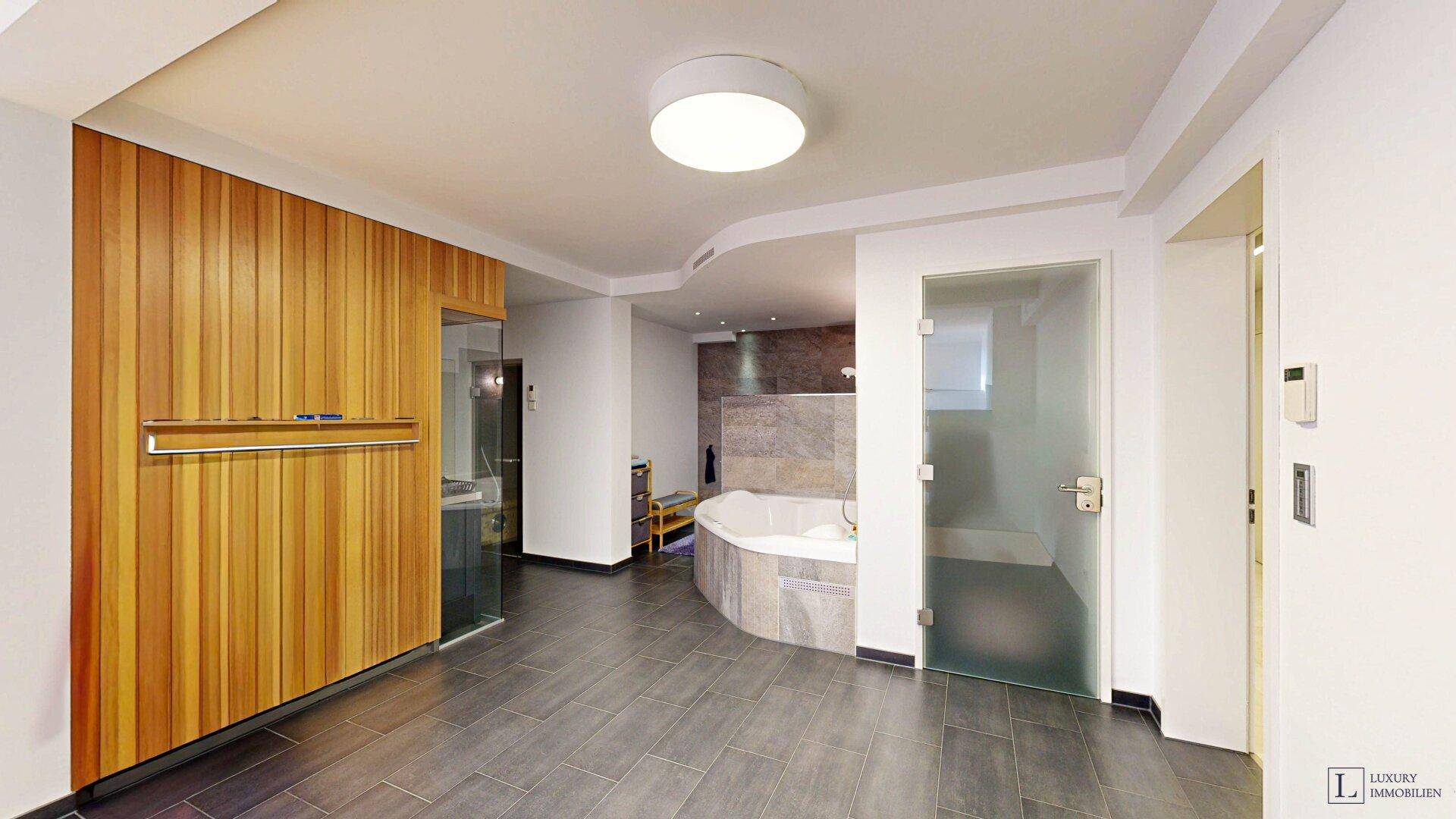 Exklusiver Wellnessbereich mit Whirlpool, Sauna und Fliesenboden.