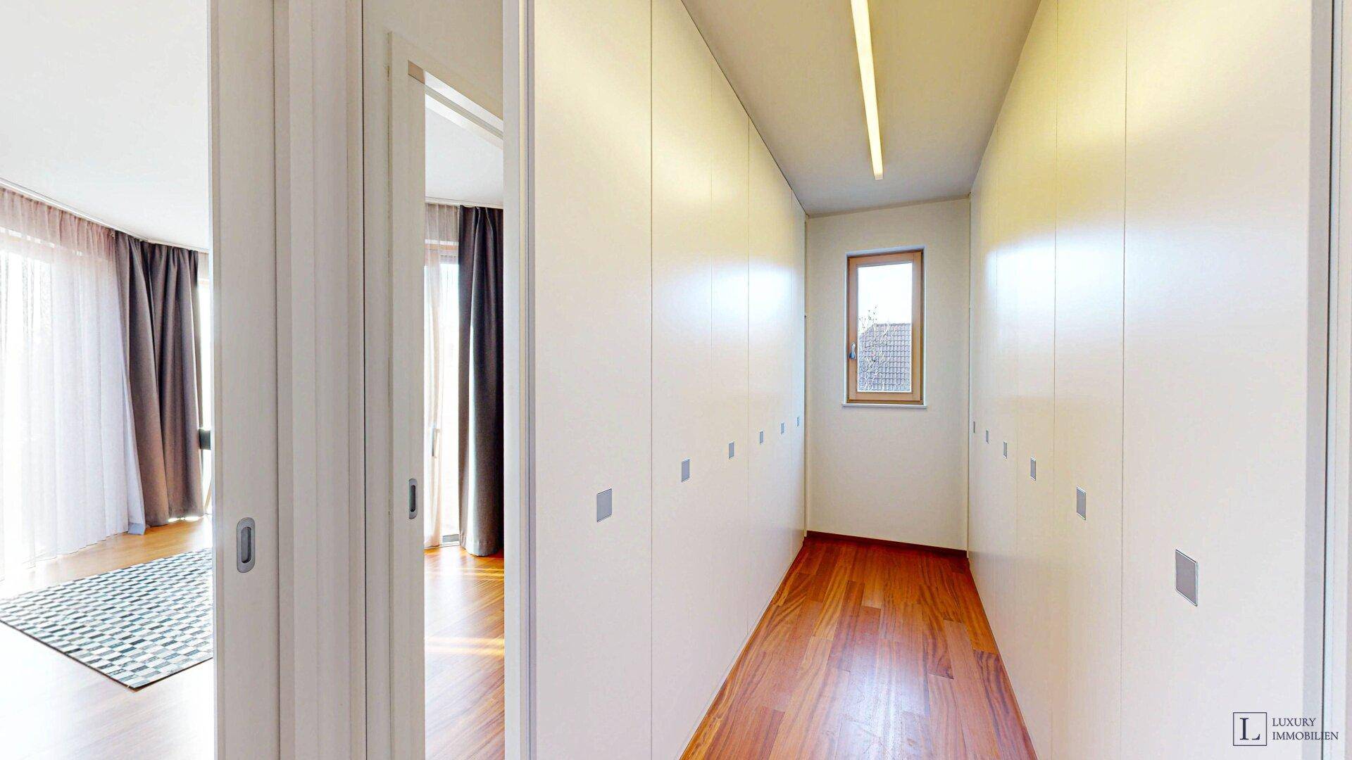 Praktischer begehbarer Kleiderschrank mit viel Stauraum und Fenster.