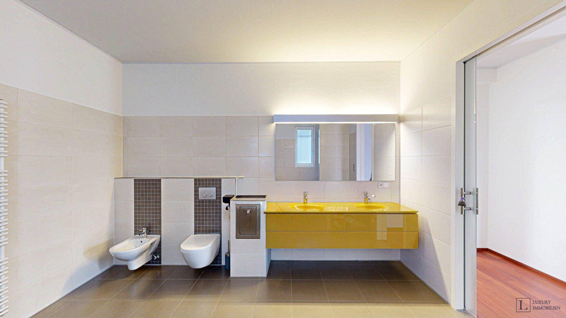 Helles Badezimmer mit Doppelwaschbecken, Bidet und modernem Spiegelschrank.