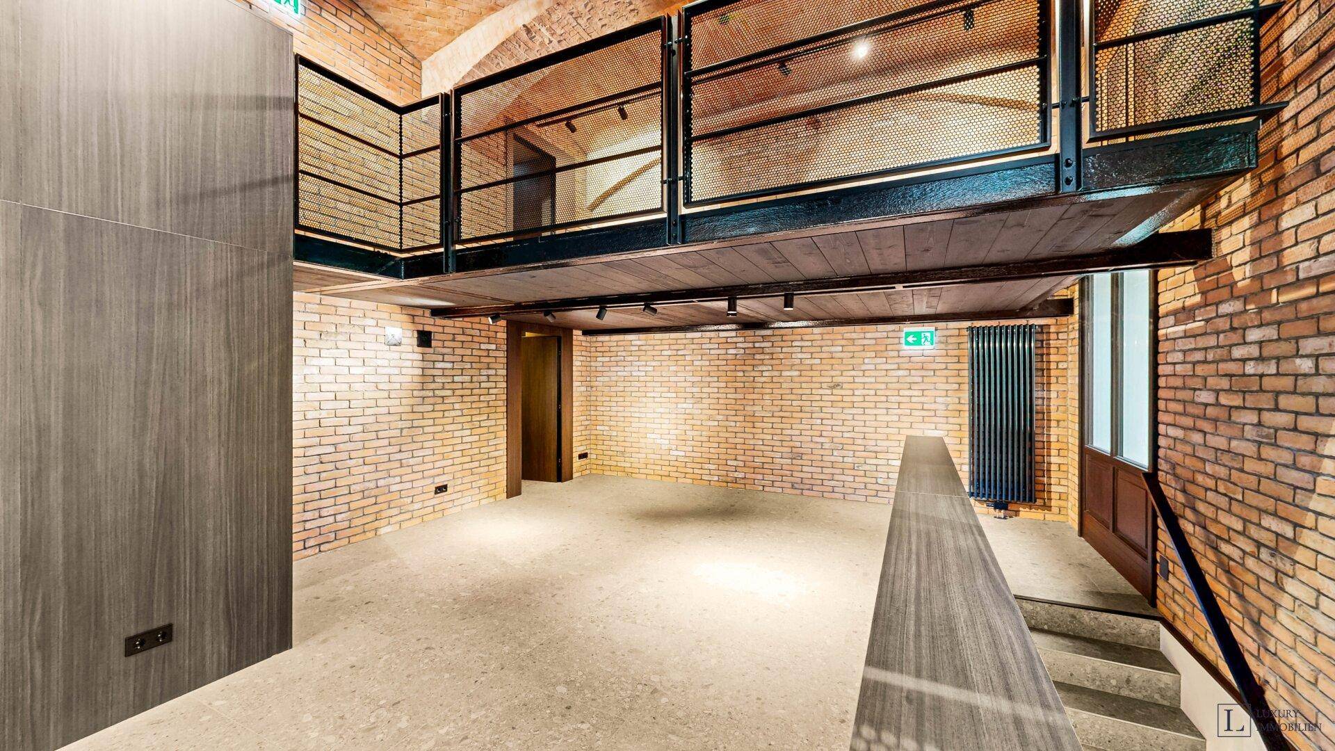 Offener Gewerberaum mit Galerie, Ziegelwänden und hohen Decken, ideal für flexible Nutzung.