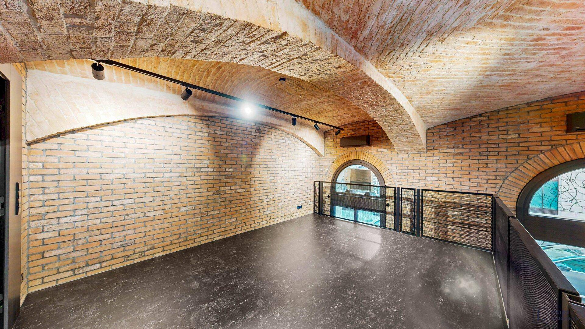 Obere Galerieebene eines Gewerberaums mit Ziegelgewölbedecke und Blick durch die Fenster.