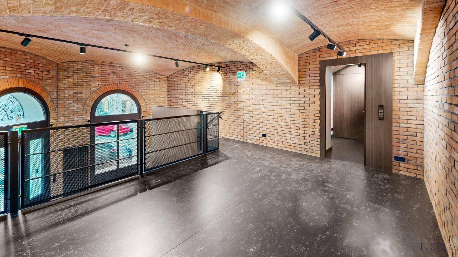 Galeriebereich mit Ziegelwänden, Gewölbedecke und modernen Fenstern, ideal für Büros oder Ausstellungsflächen.
