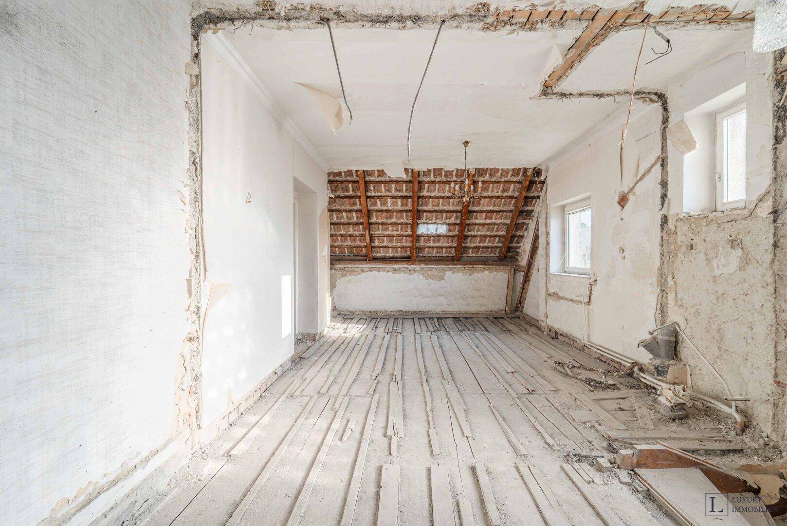Unausgebauter Dachbodenraum mit freiliegenden Holzdielen und sichtbarer Dachkonstruktion, ideal für den Ausbau.
