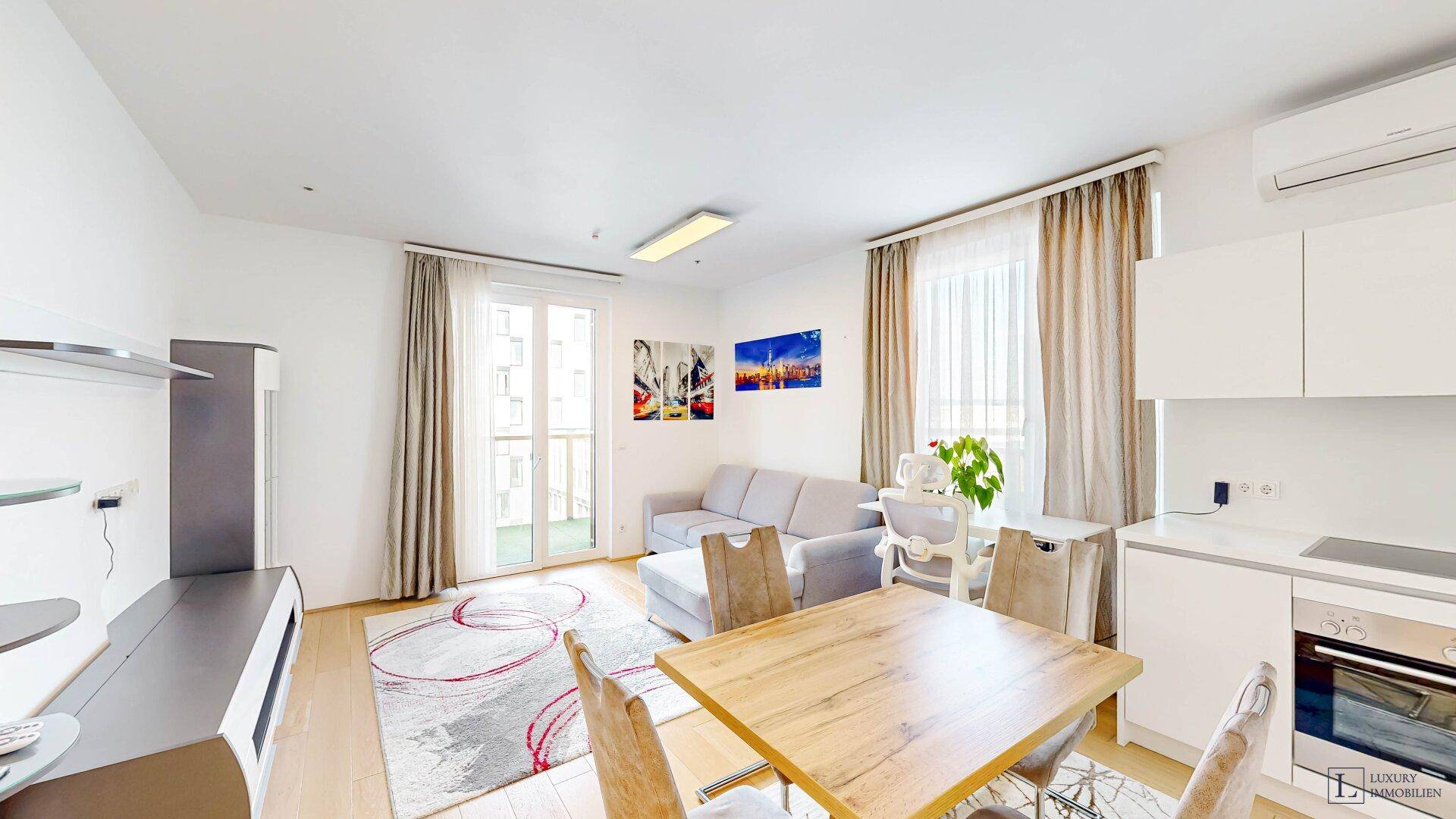 Heller Wohn-Essbereich mit Holztisch, Sofa und Zugang zum Balkon, ausgestattet mit Klimaanlage.