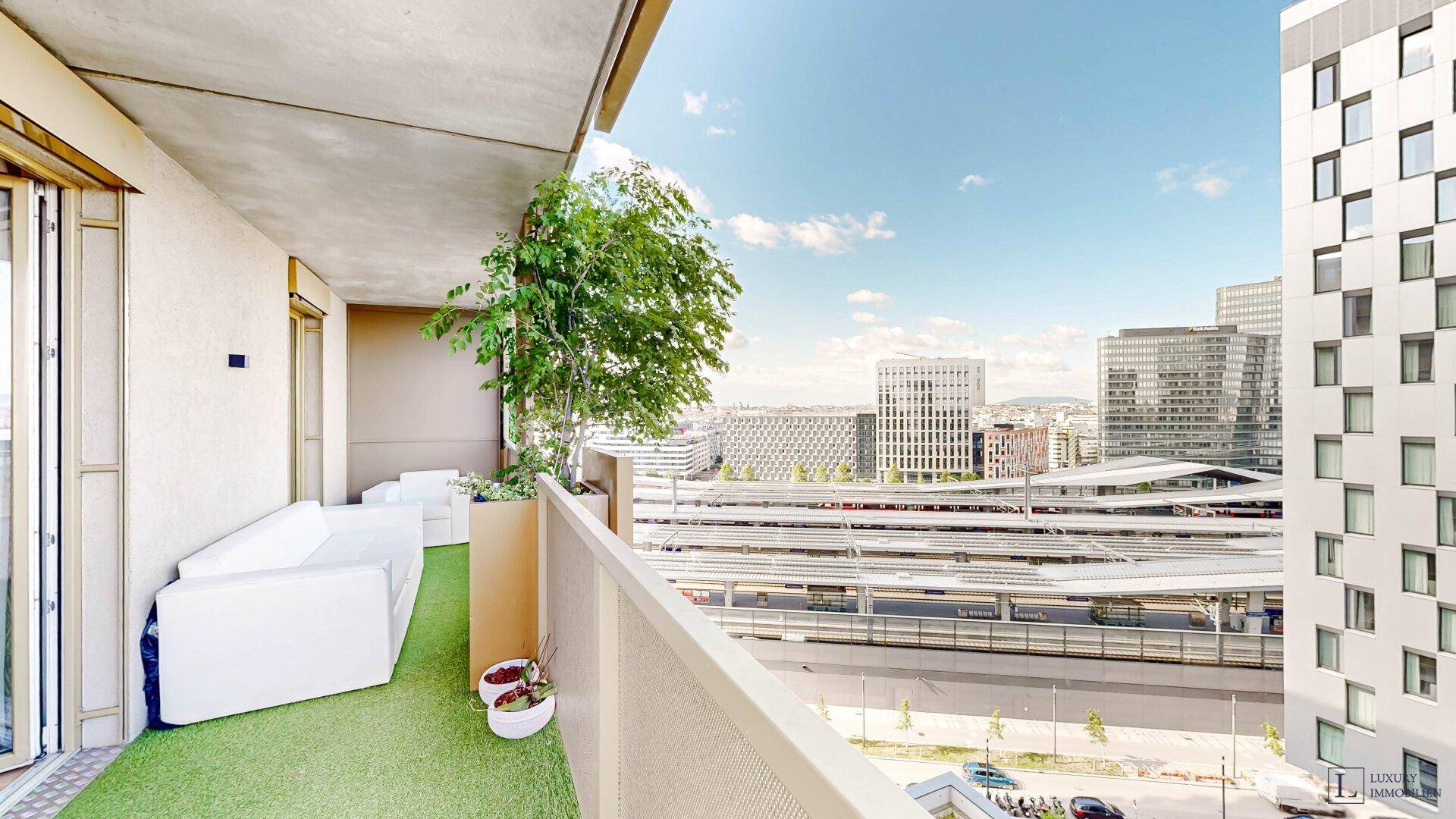 Geräumiger Balkon mit Loungemöbeln und weitem Blick über die Stadt und Bahnanlagen.