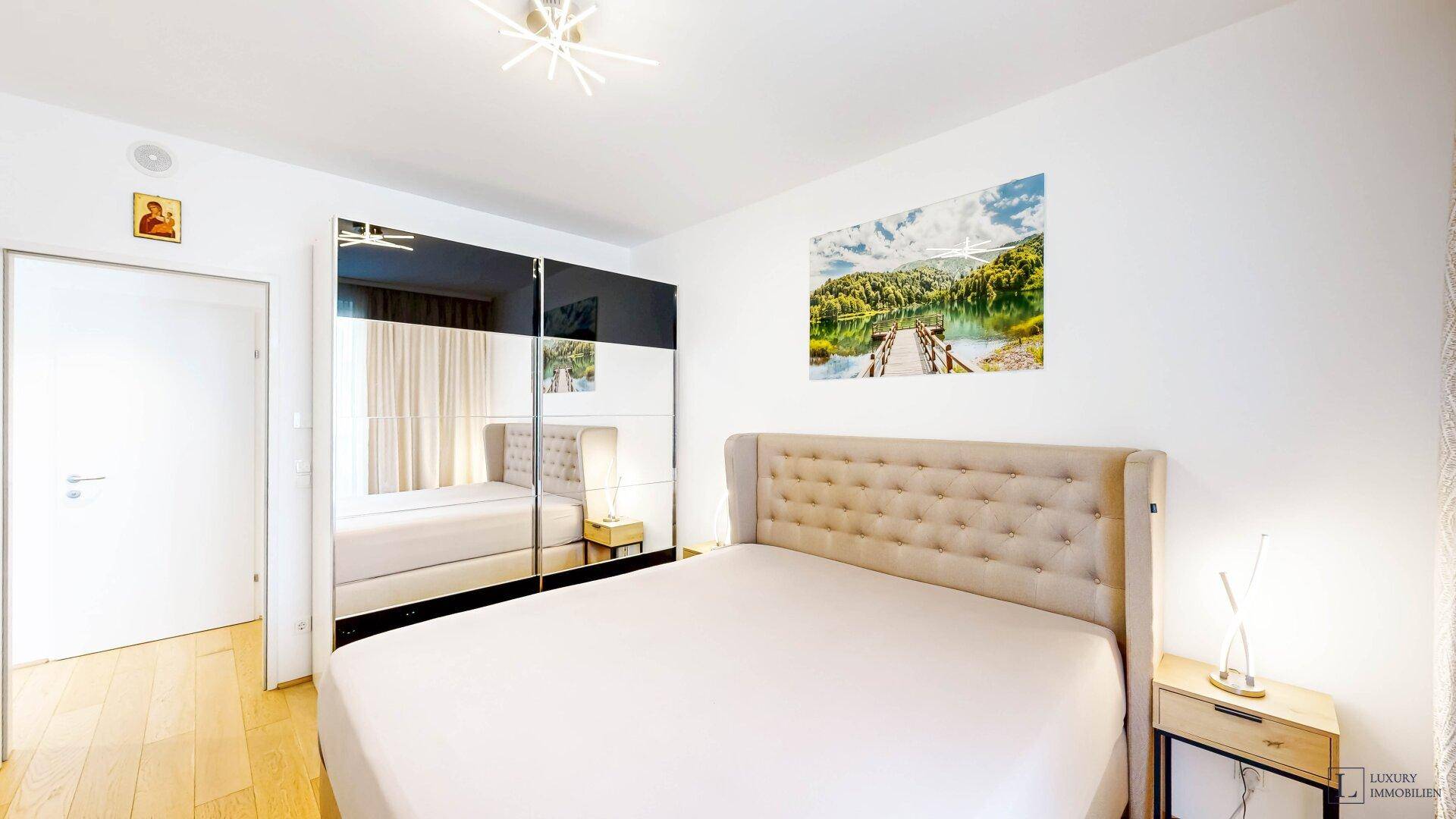 Helles Schlafzimmer mit großem Bett, Spiegelschrank und Holzboden, modern eingerichtet.