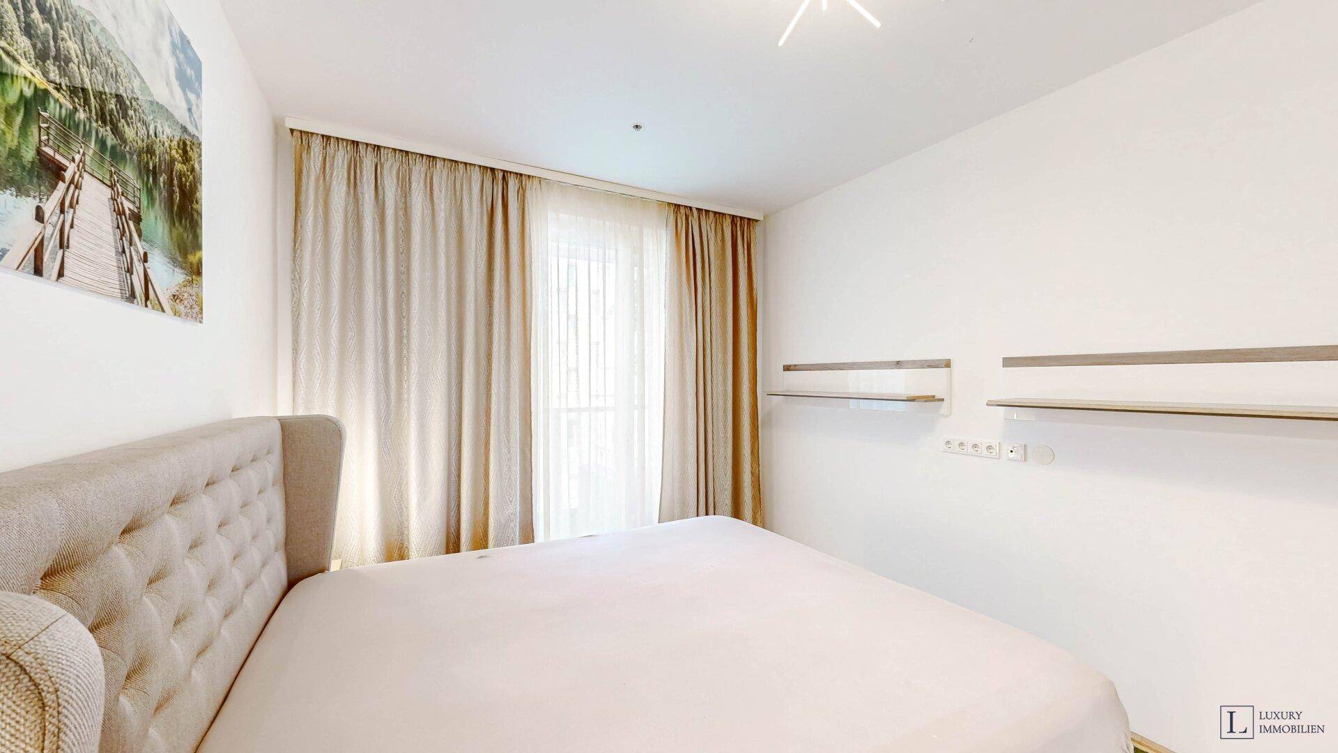 Schlafzimmer mit großem Fenster, Vorhängen und Wandregalen, bietet eine ruhige Atmosphäre.