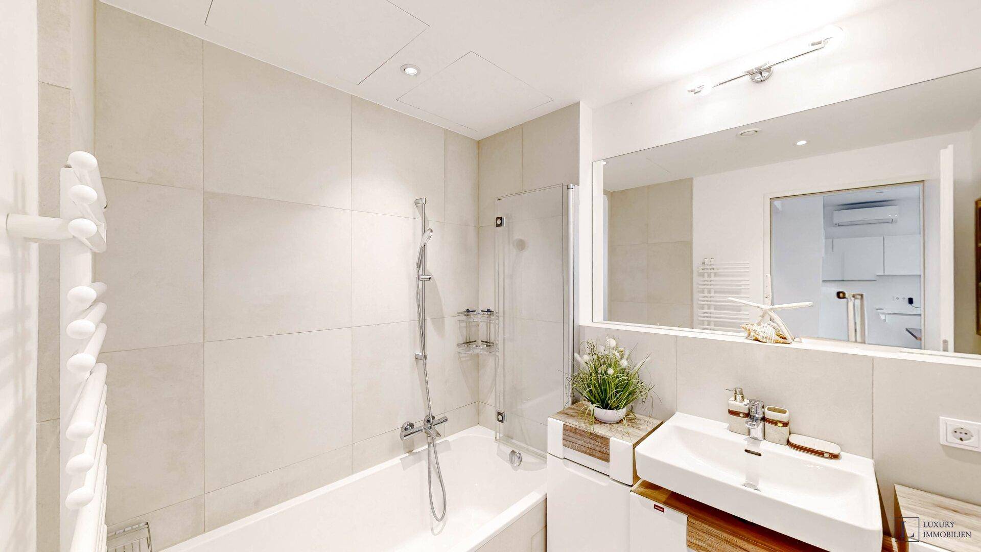 Modernes Badezimmer mit Badewanne, Duschbereich, Waschbecken und beheiztem Handtuchhalter.
