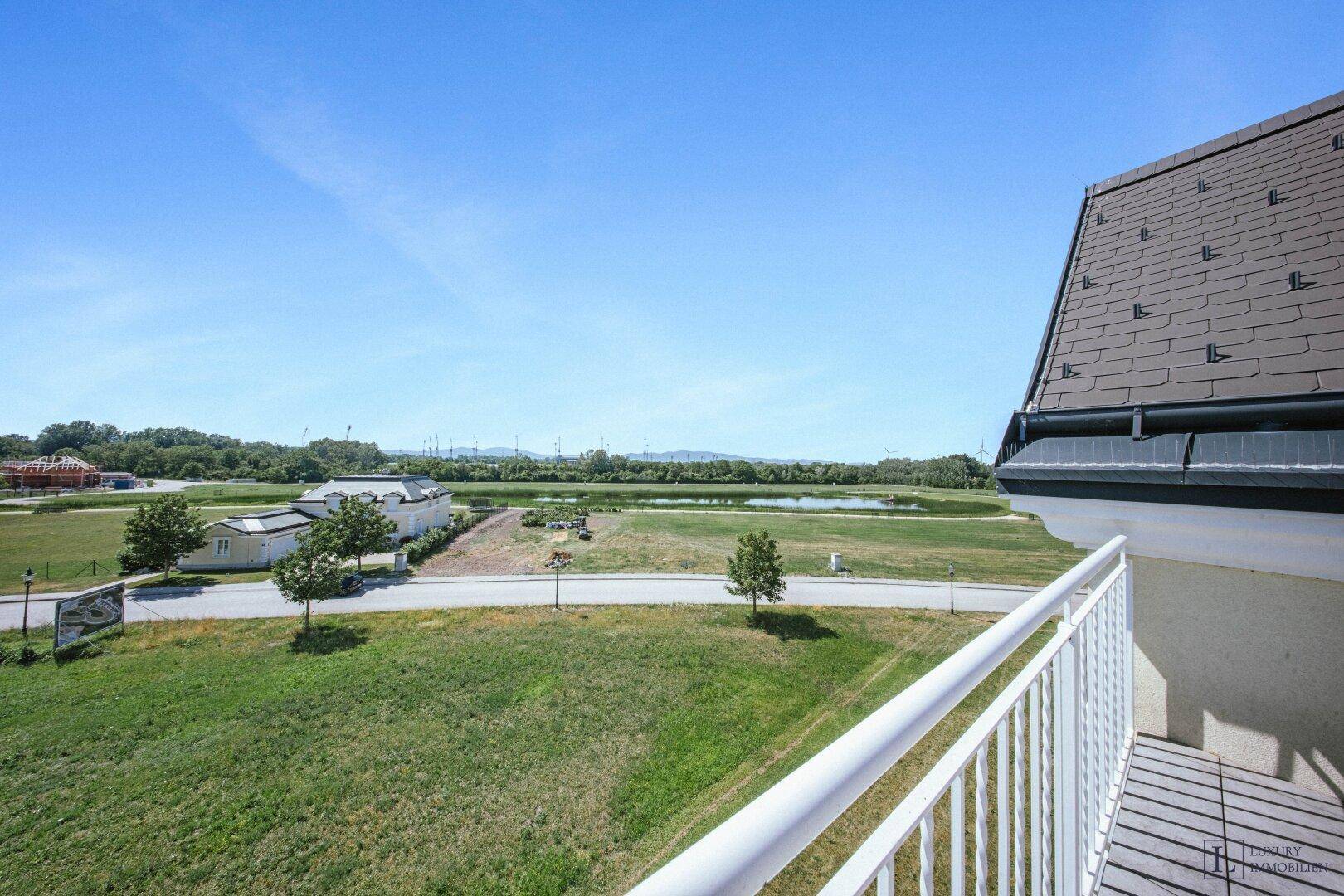 Balkon mit weitem Blick über grüne Wiesen, einen Teich und die ländliche Umgebung.