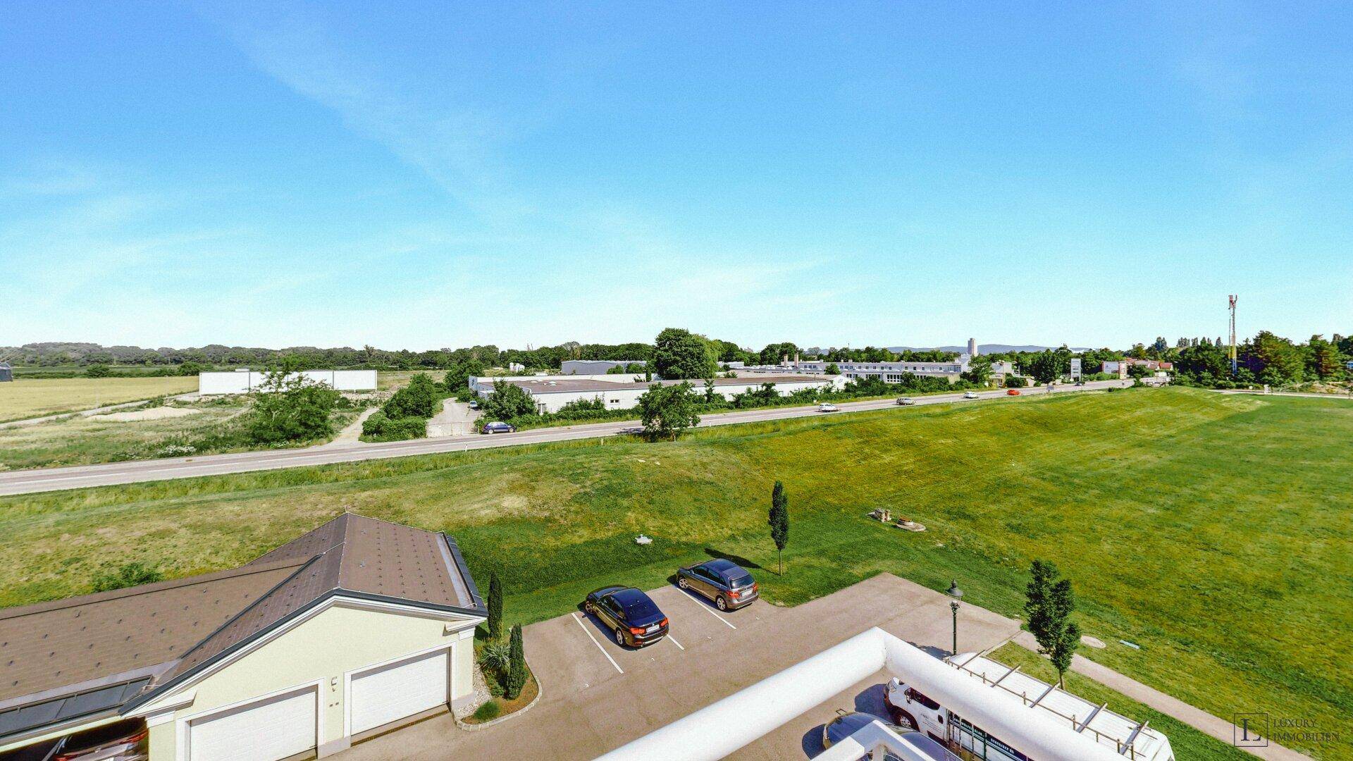 Luftaufnahme der Wohnanlage mit Parkplätzen, grünen Flächen und umliegender Landschaft.
