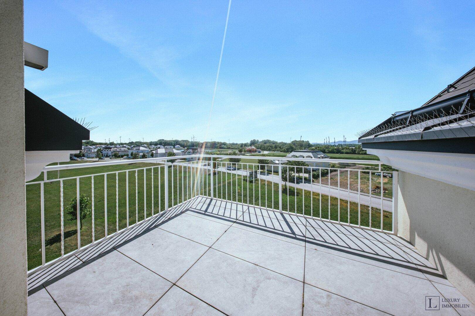 Großer Balkon mit weitem Blick über grüne Felder und die umliegende Landschaft.