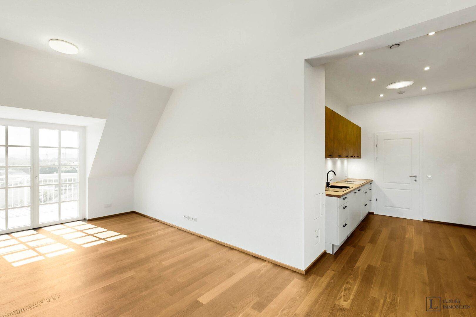 Heller Wohnbereich mit Holzboden, Dachschrägen und Zugang zu einem französischen Balkon.