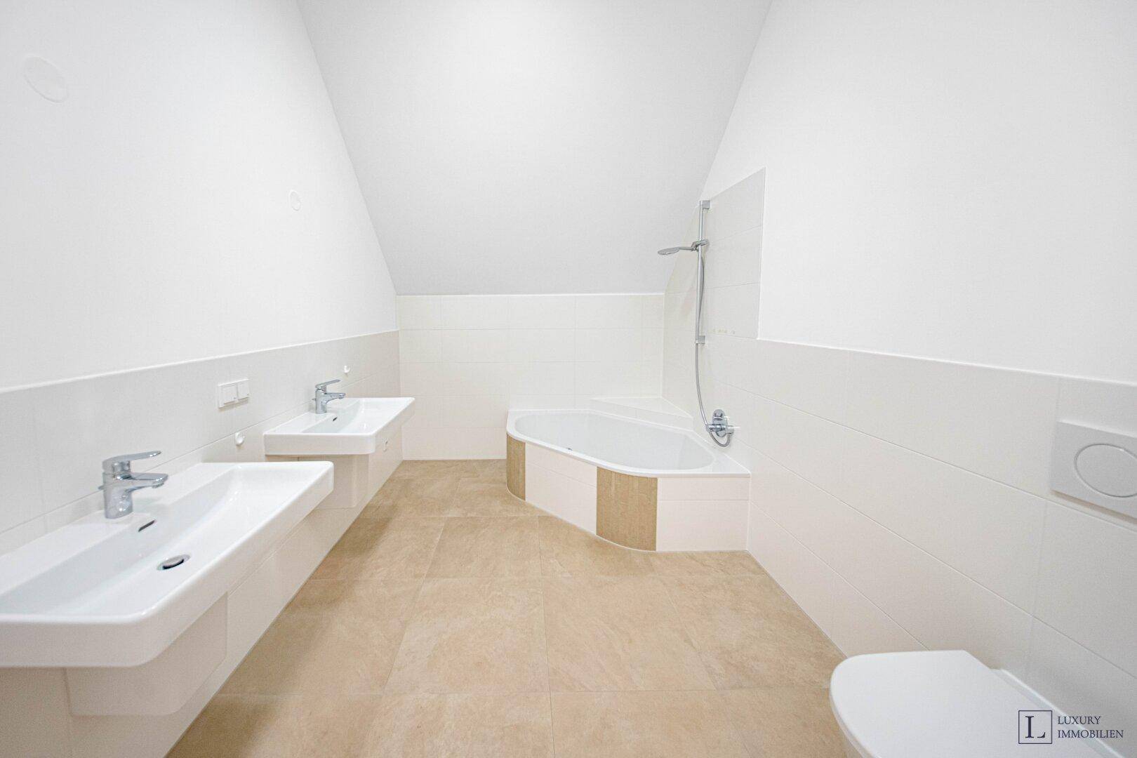 Modernes Badezimmer mit Doppelwaschbecken, Badewanne und hellen Fliesen.