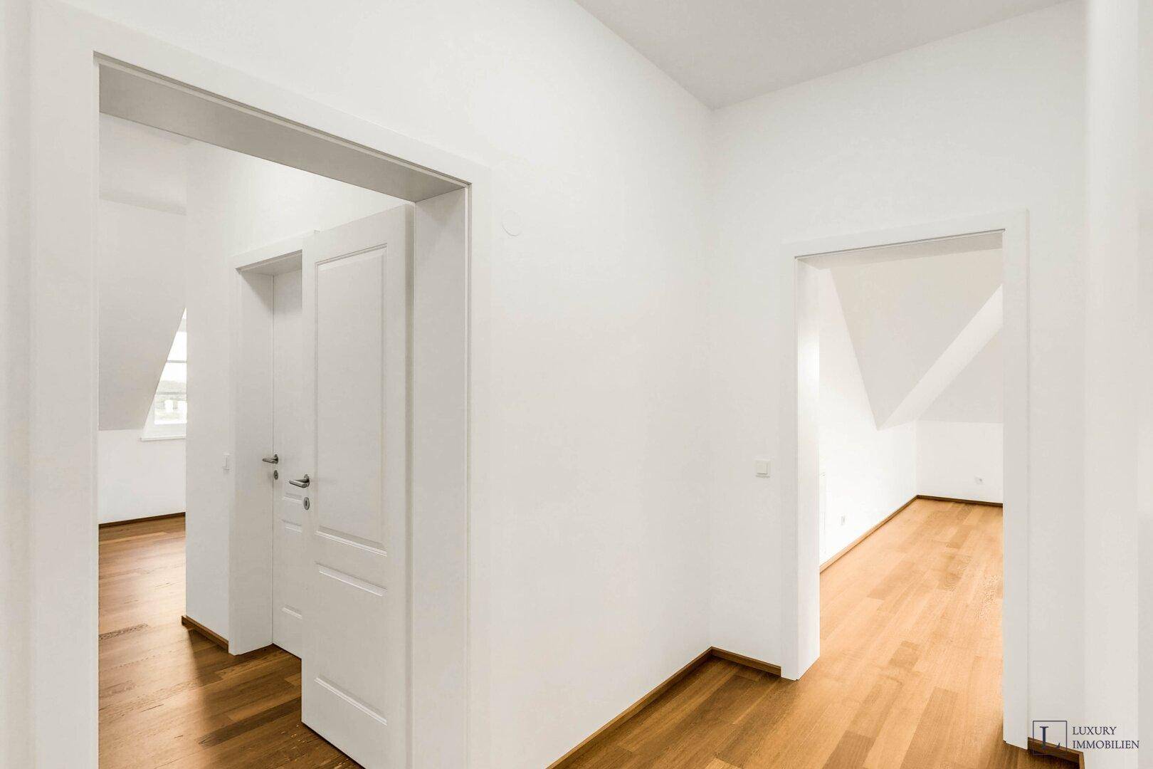 Heller Flurbereich mit Holzboden und weißen Türen, der zu weiteren Räumen führt.