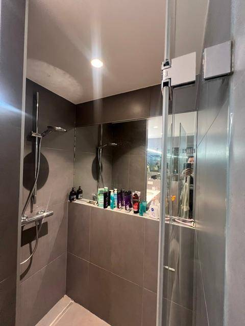 Moderne Duschkabine mit grauen Fliesen und Glasabtrennung im Badezimmer.