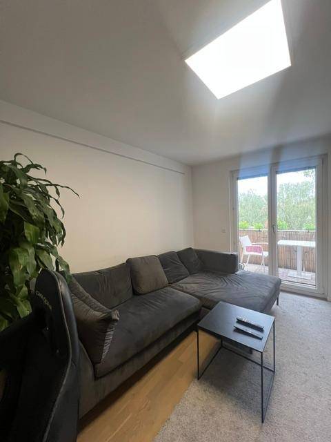 Helles Wohnzimmer mit gemütlichem Ecksofa, Couchtisch und Zugang zu einem Balkon.