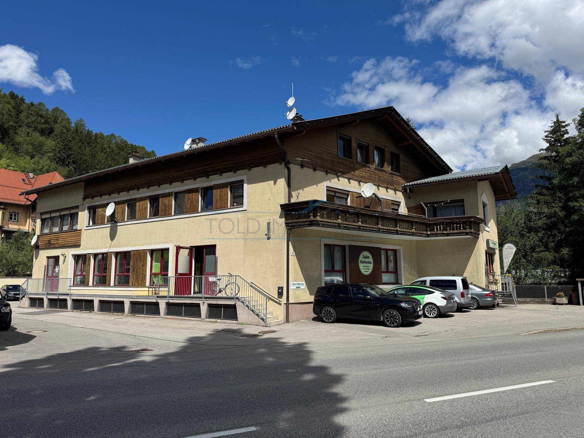 Ansicht des Gebäudes von der Straße mit Holzelementen, Balkonen und alpiner Architektur.