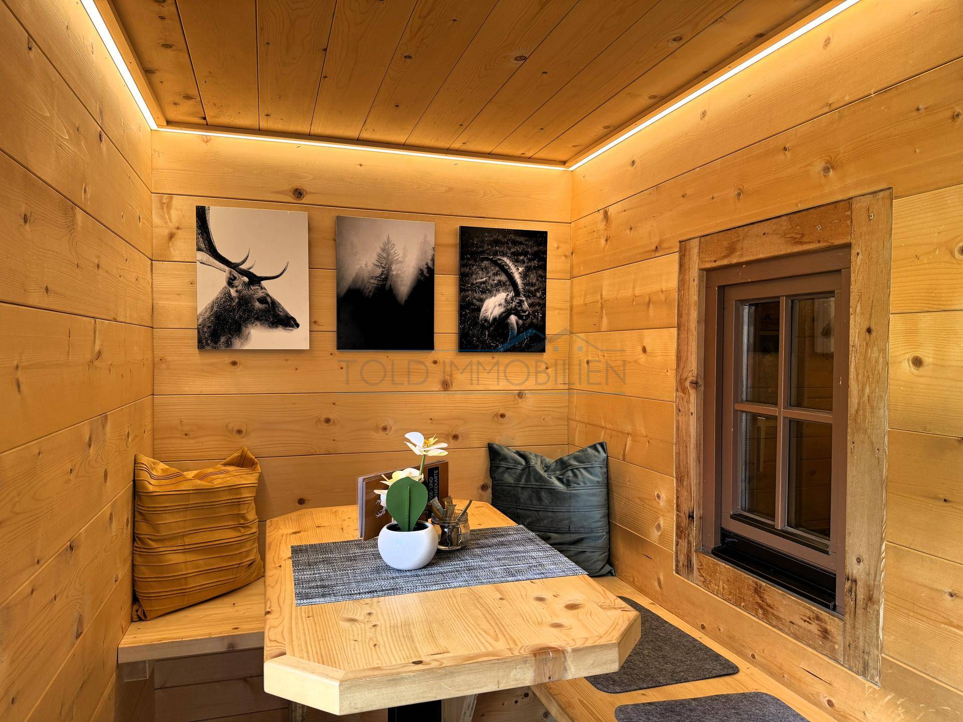 Gemütlicher Essbereich mit Holztäfelung, eingebauter Sitzbank und dekorativen Bildern an der Wand.