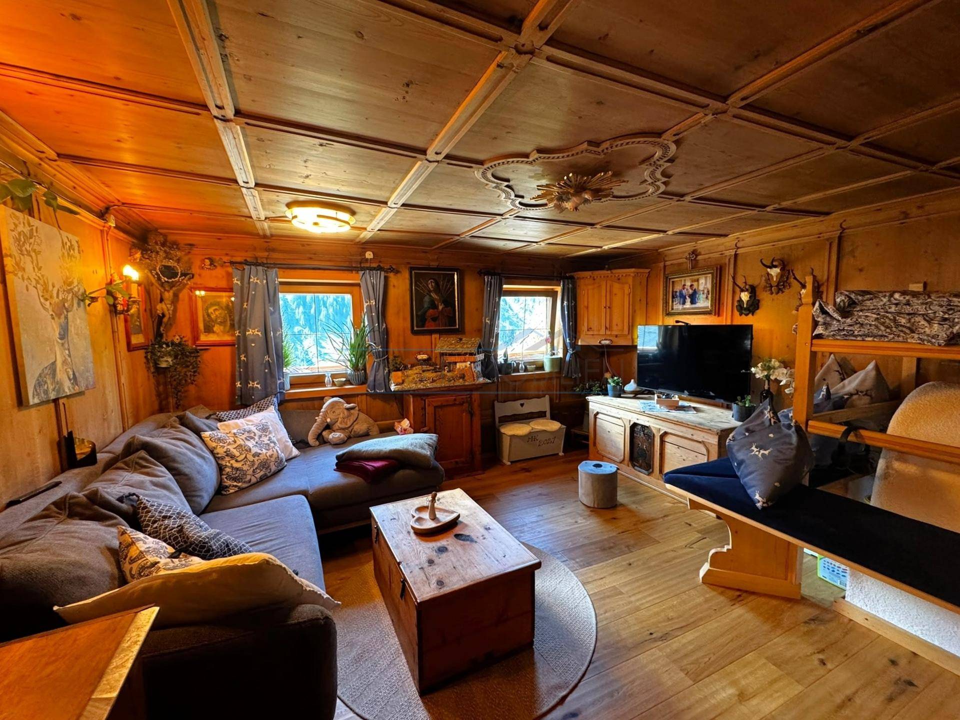 Rustikales Wohnzimmer mit Holzboden, bequemer Couch und traditioneller Deckenverkleidung.