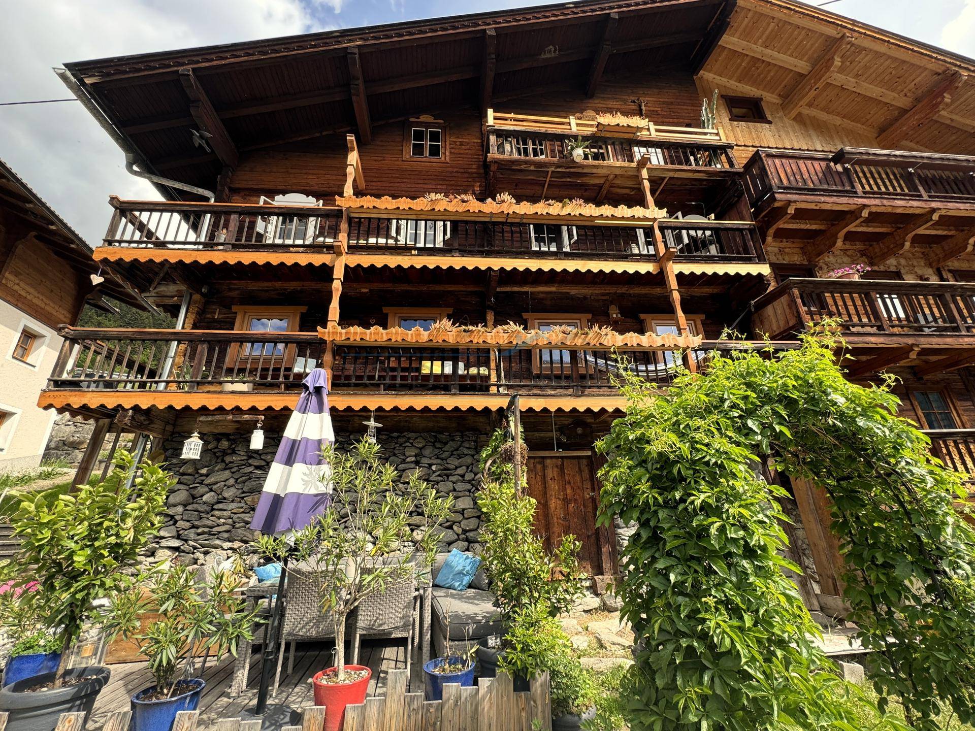 Gemütliche Terrasse mit Sitzgelegenheiten und Blick auf das traditionelle Holzhaus.