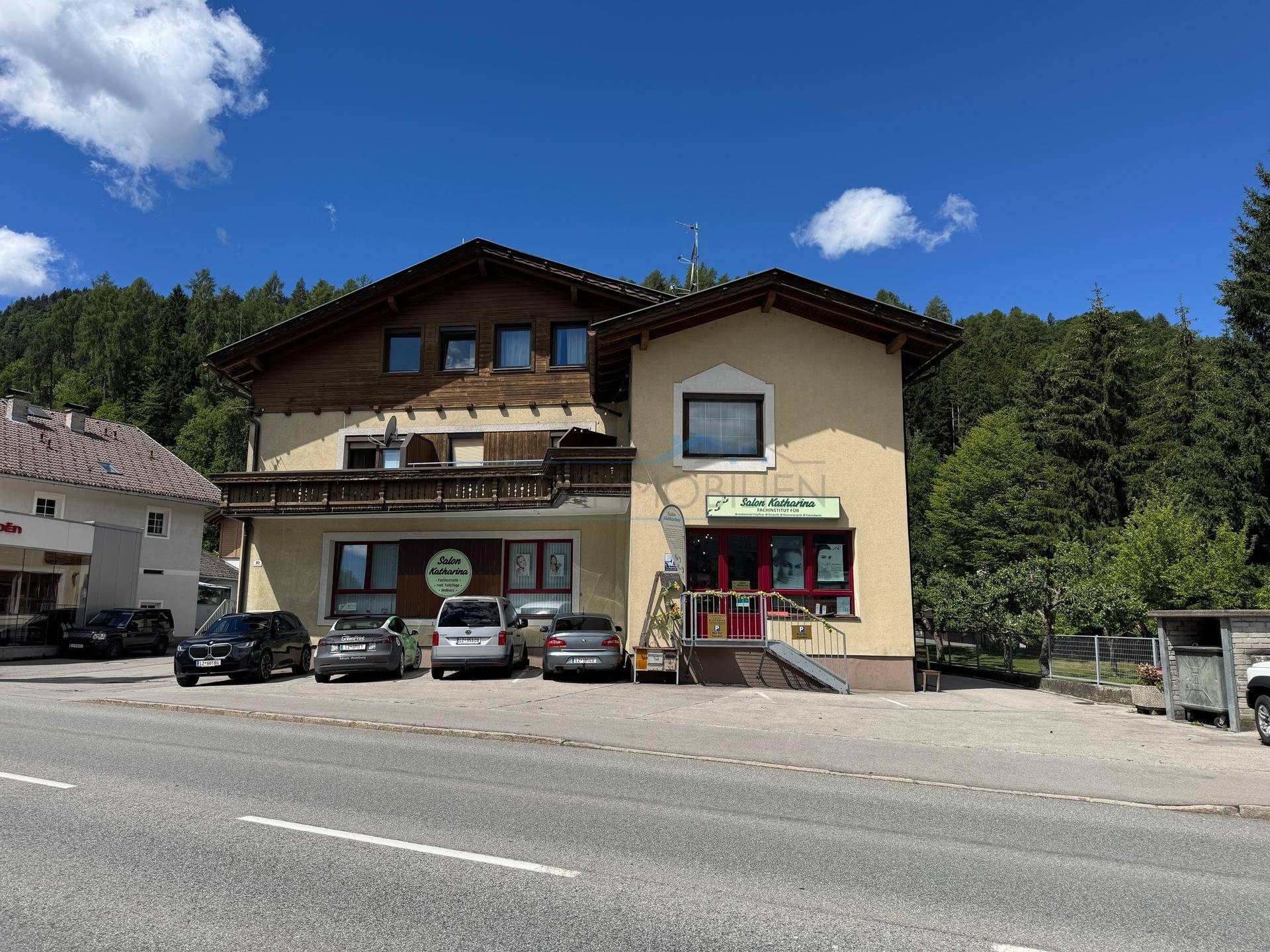 Fassade des Gebäudes mit Geschäften im Erdgeschoss und traditionellen Holzbalkonen.